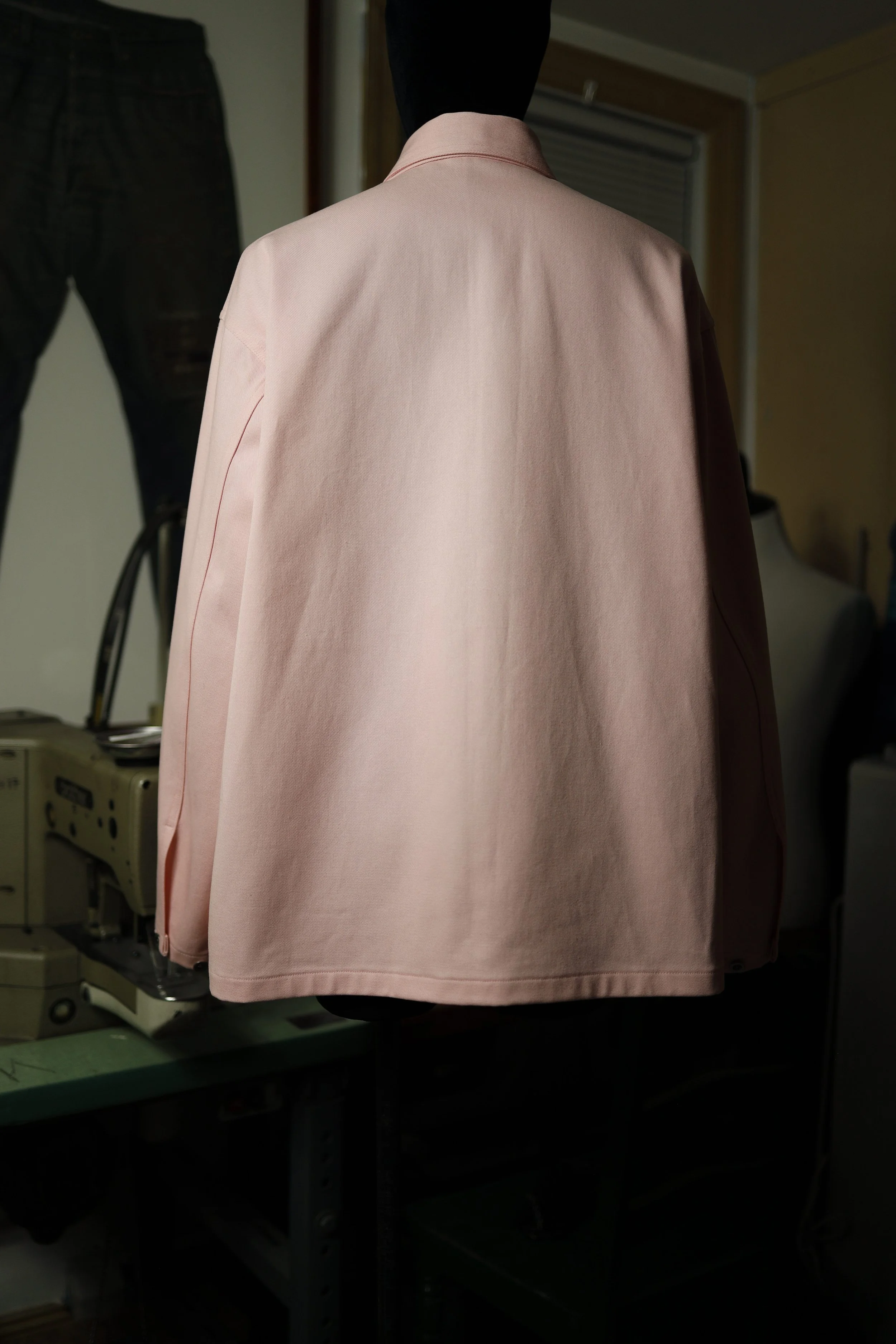 Back view of a rose pink cotton denim pullover shirt showcasing clean lines, textured fabric, and artisanal construction.