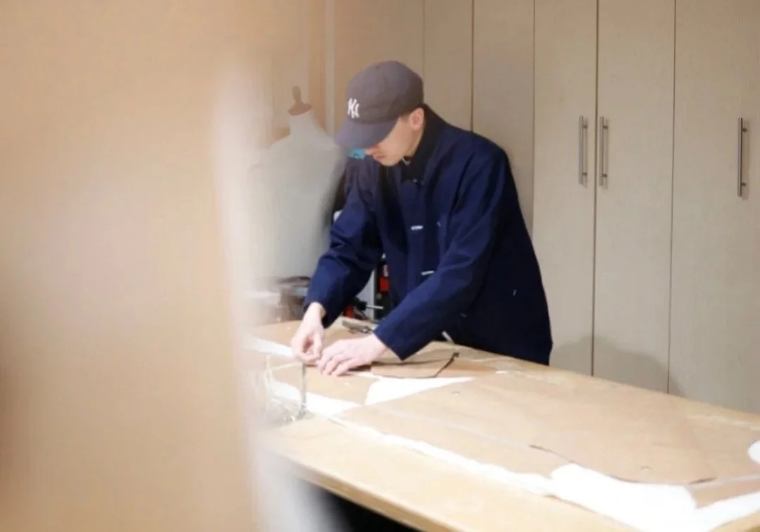 Garment maker reviewing and adjusting paper patterns on a cutting table before production in a small clothing atelier