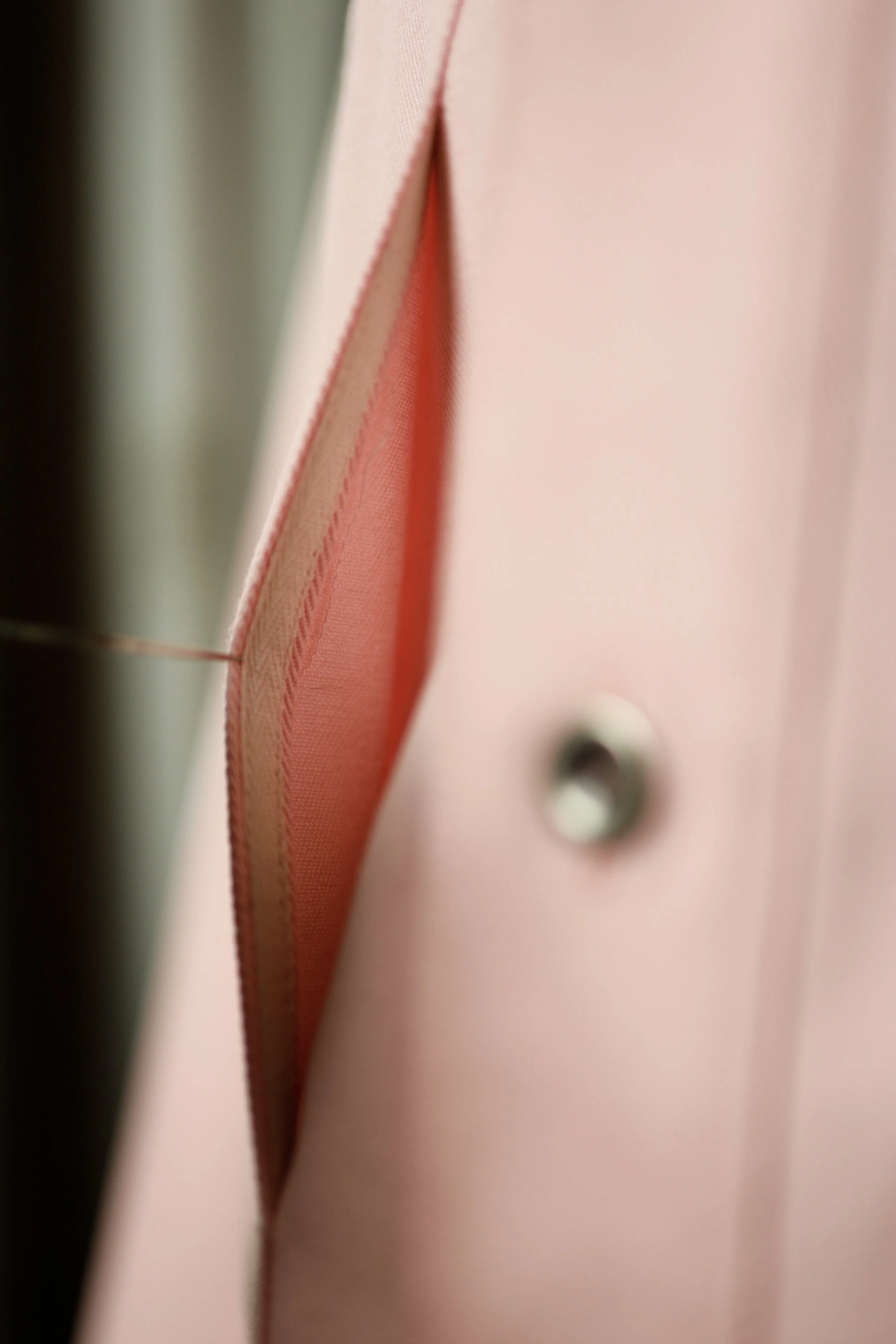 Close-up of the interior placket and construction details of a rose pink cotton denim pullover shirt.