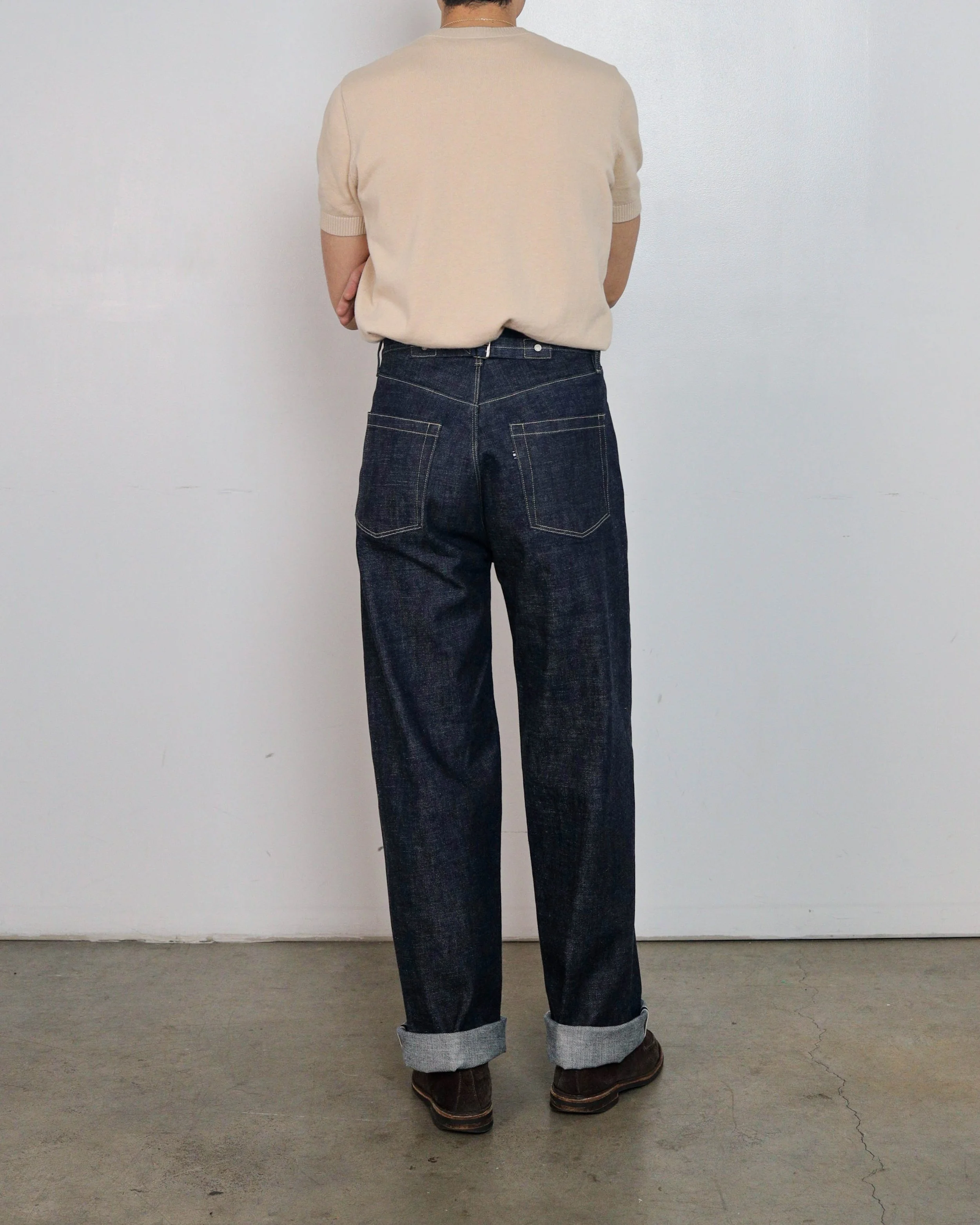 On‑body back view of indigo selvedge denim jeans by [ko’lōn], showing rear pocket construction, back waistband, and straight‑leg fit.
