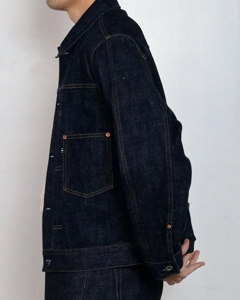 Detail of selvedge denim work jacket front patch pocket and exposed buttons