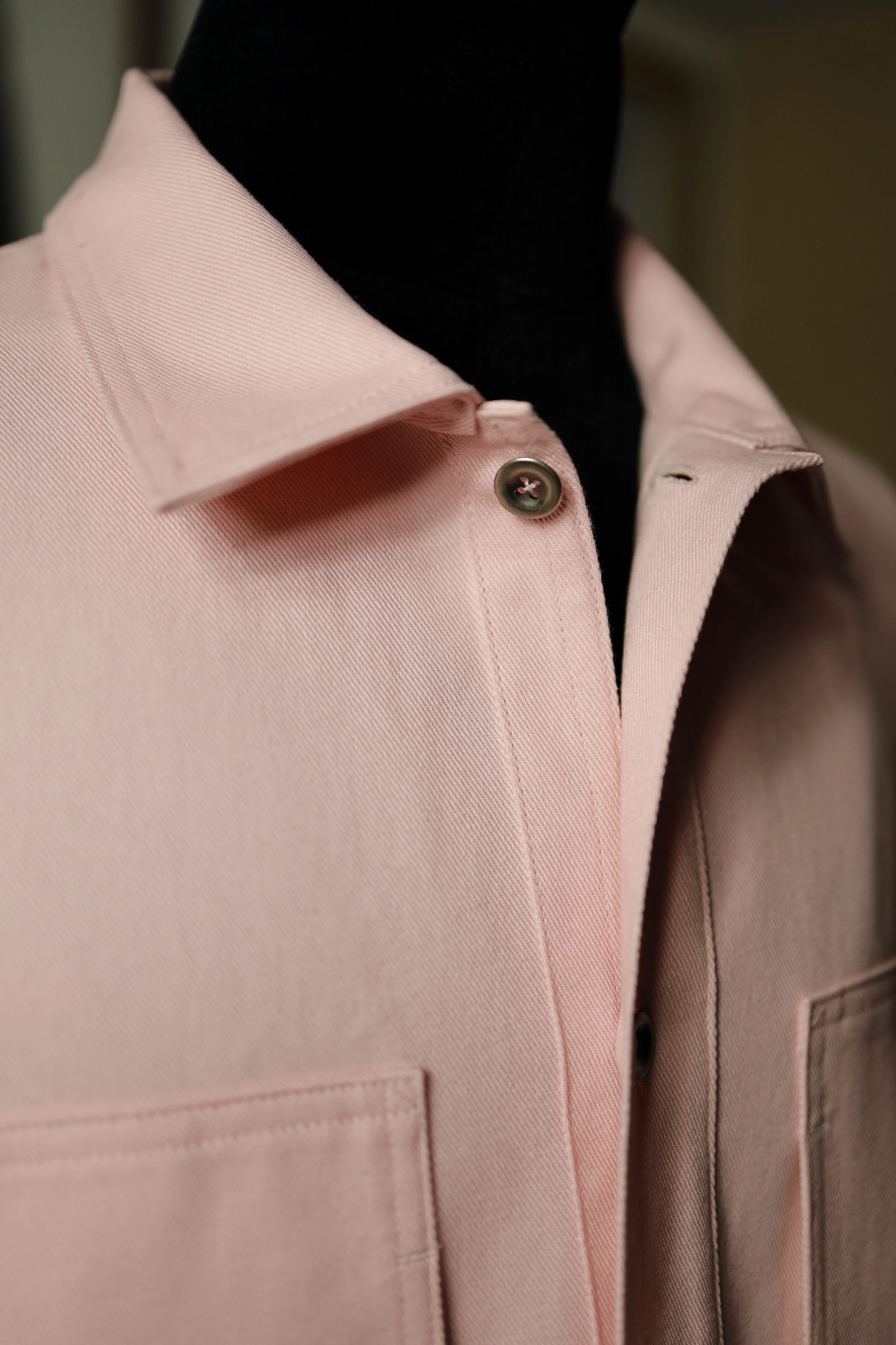 Detailed view of the collar and placket on a rose pink cotton denim pullover shirt with refined stitching and structured construction.