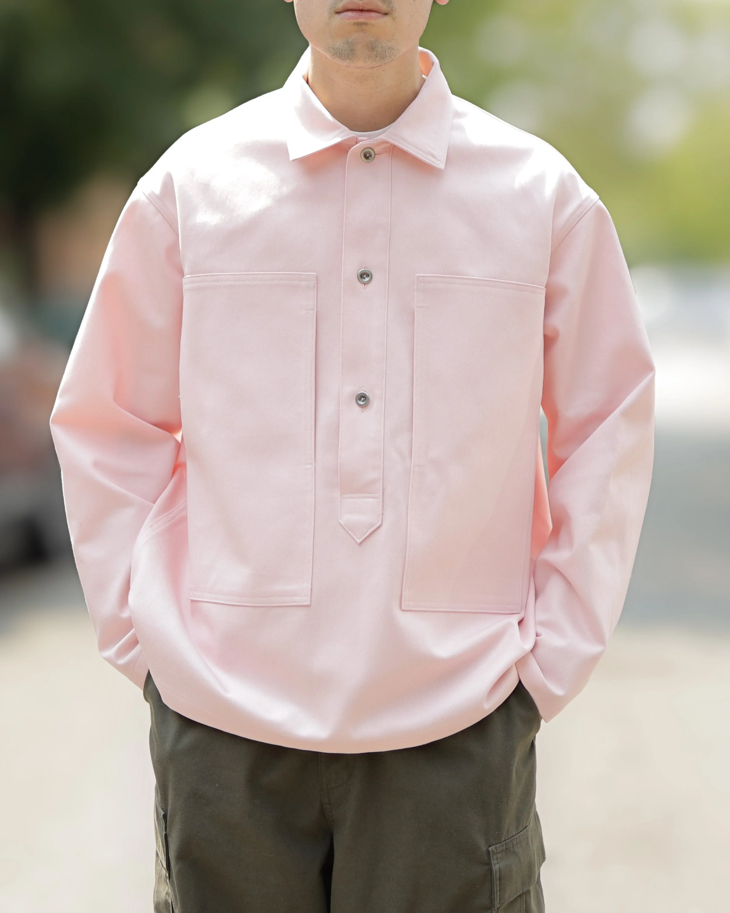 Model wearing the Rose Cotton Denim Pullover Shirt featuring a relaxed oversized fit, utility pockets, and soft pink cotton denim fabric styled for everyday contemporary wear.