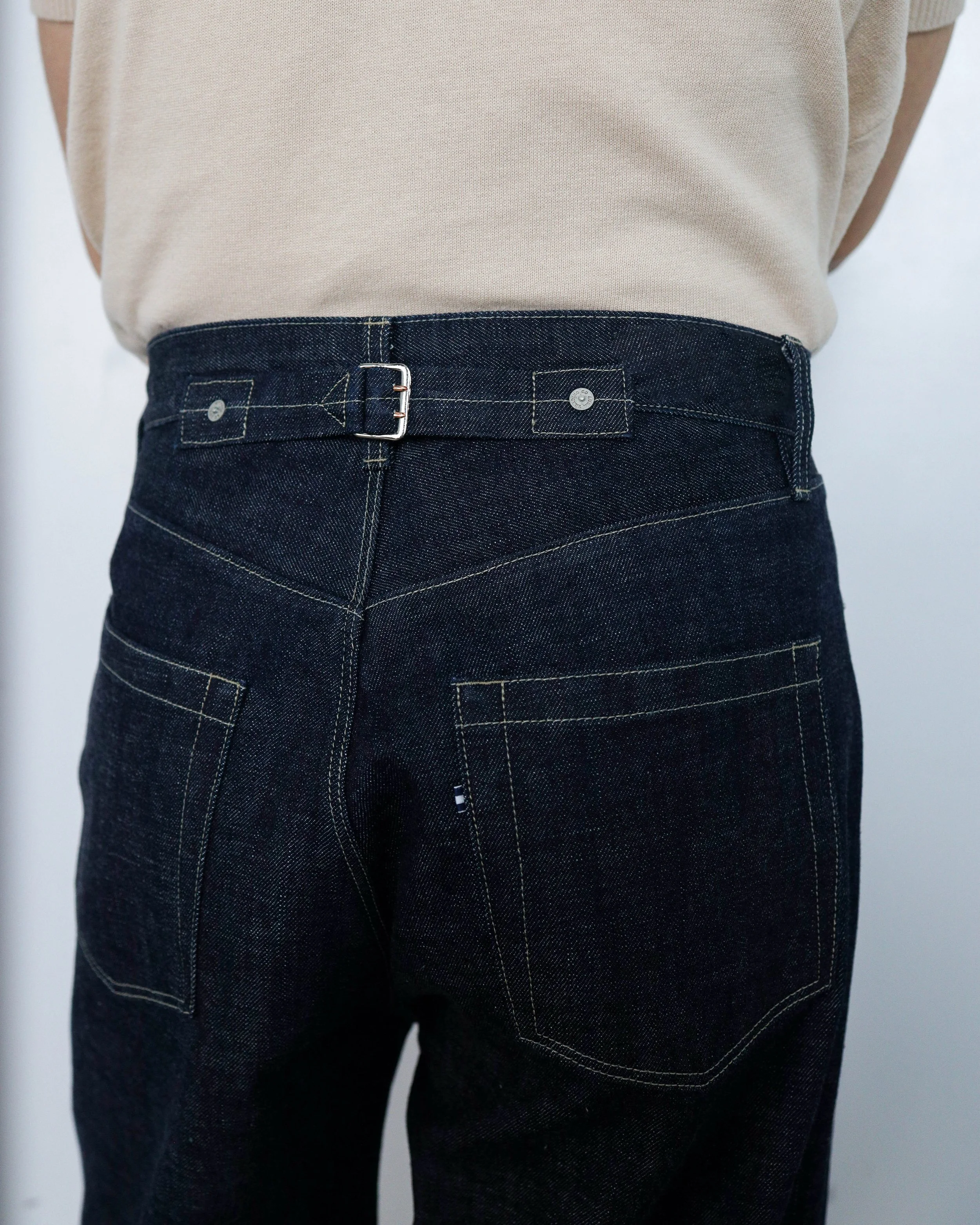 Close‑up detail of the back pocket and waistband on indigo selvedge denim jeans by [ko’lōn], showing construction, stitching, and hardware.