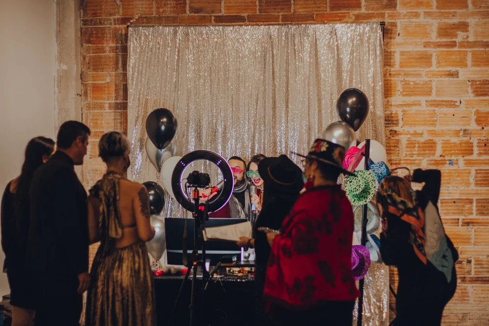 Guests gathered at a branded photo booth with balloons and a gold backdrop at a Texas event