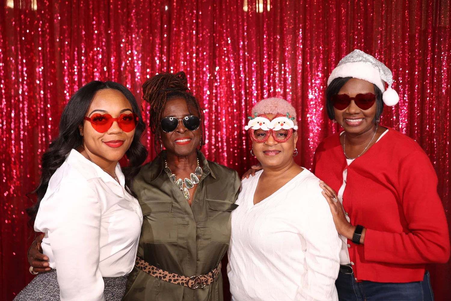 Four coworkers in sunglasses posing at a OneAway Studios photo booth with a red sequin backdrop