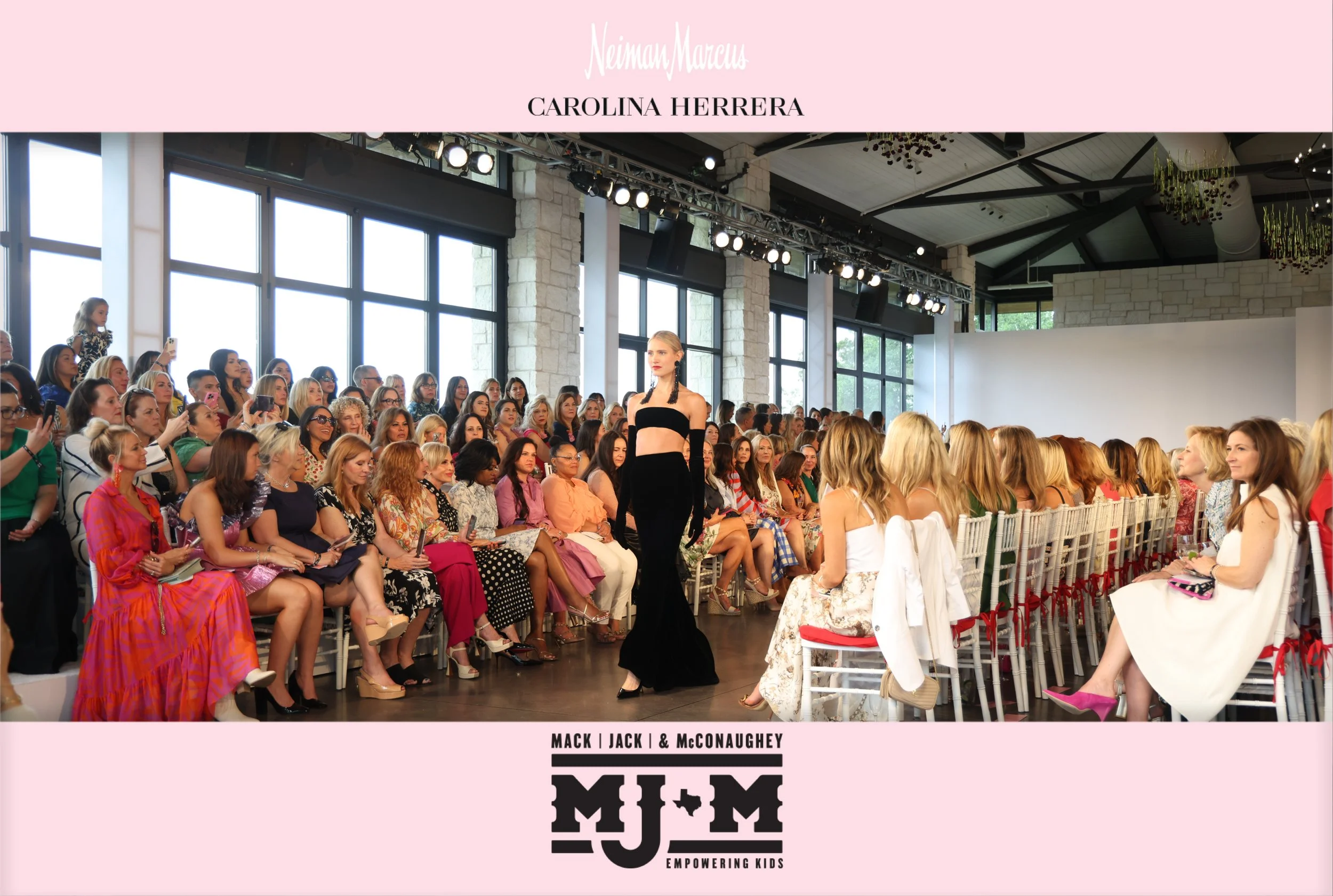 Model walking the runway in a Carolina Herrera fashion show hosted by Neiman Marcus for the Mack, Jack & McConaughey Empowering Kids event, with audience watching inside a modern venue.