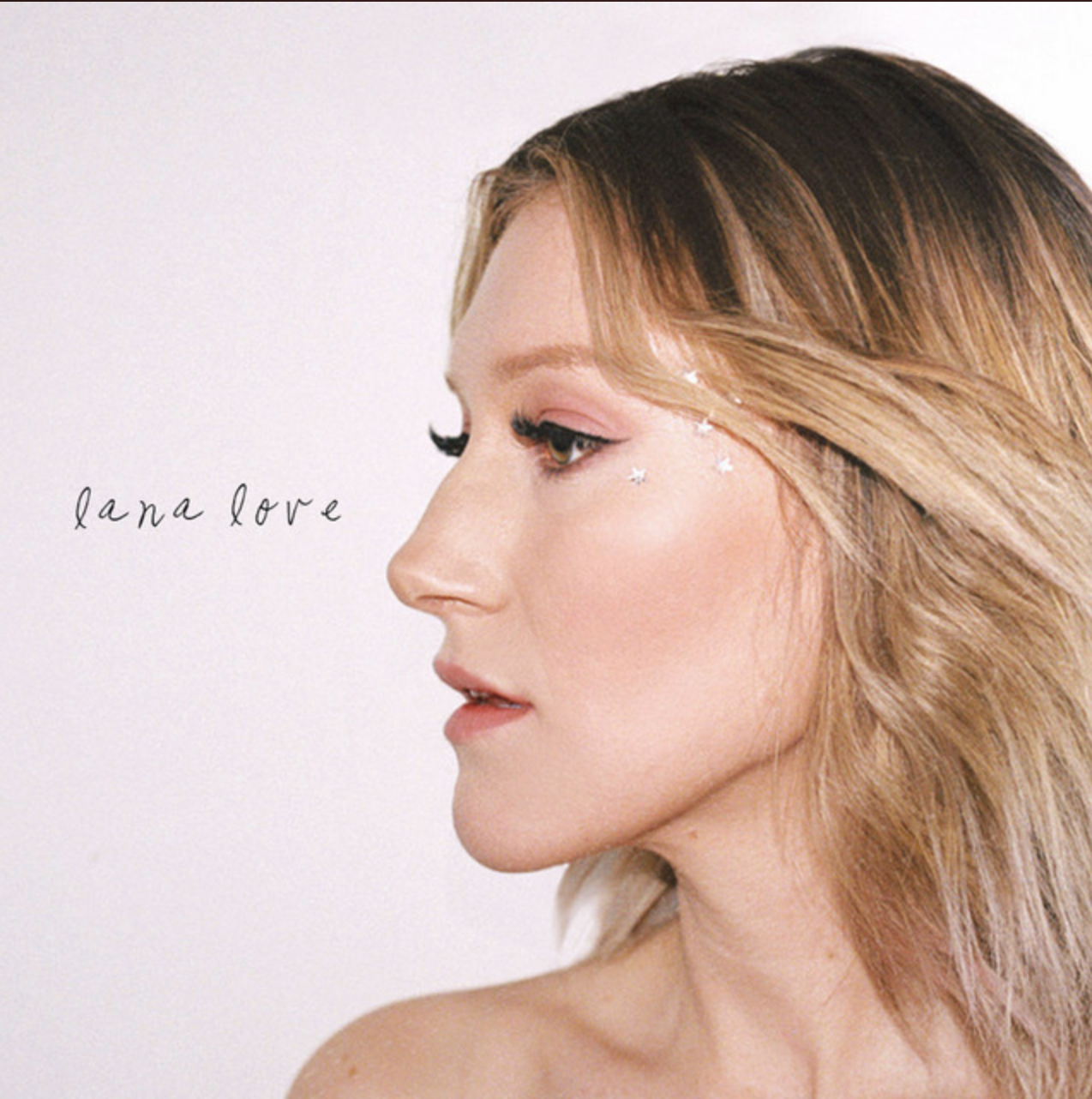 Close-up side profile of a woman with light brown hair and star-shaped face decorations, with text 'lana love' on a pale background.