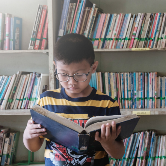 child_with_glasses_reading_in_library.png