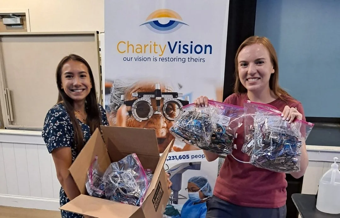 Two teens hold bags of glasses.