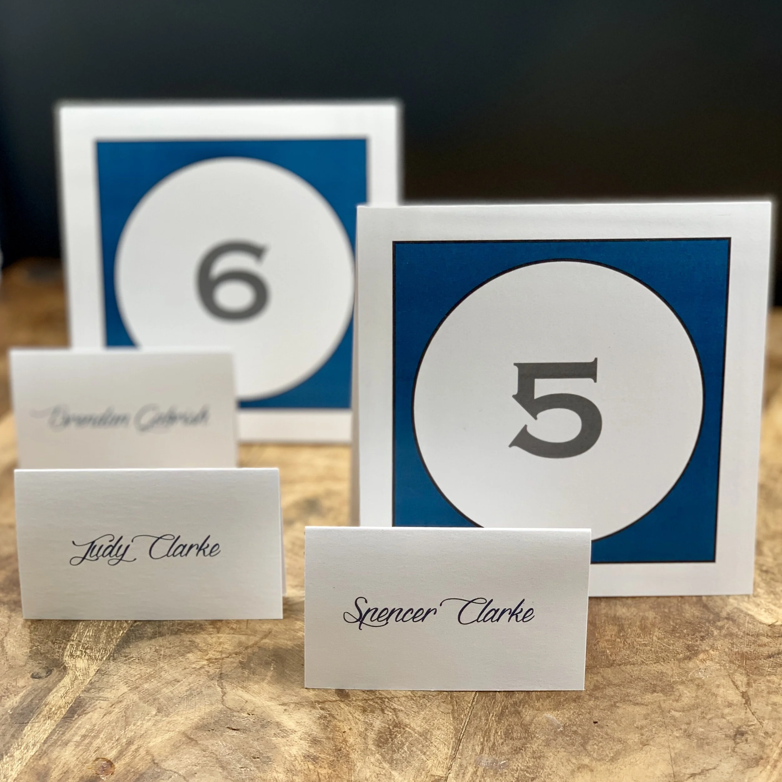 Table numbers and place cards are the final touches that tie a wedding together. Paper Moon Shop can create custom designs that match the invitation, décor, or theme—whether it’s coordinating colors or the same font as the invites. A cohesive look, p