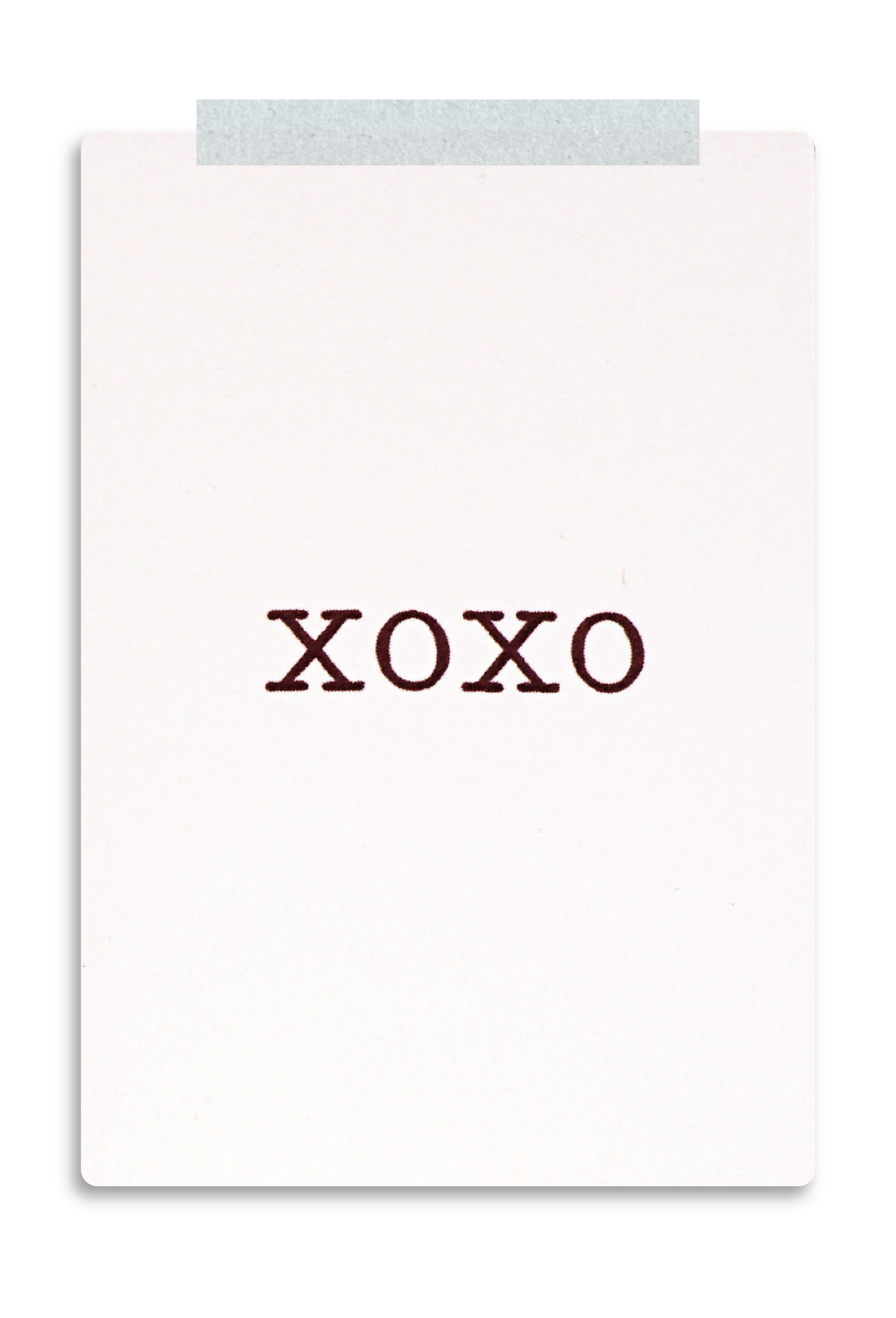 A white card with the word 'XOXO' in dark red text, taped to a grey background.