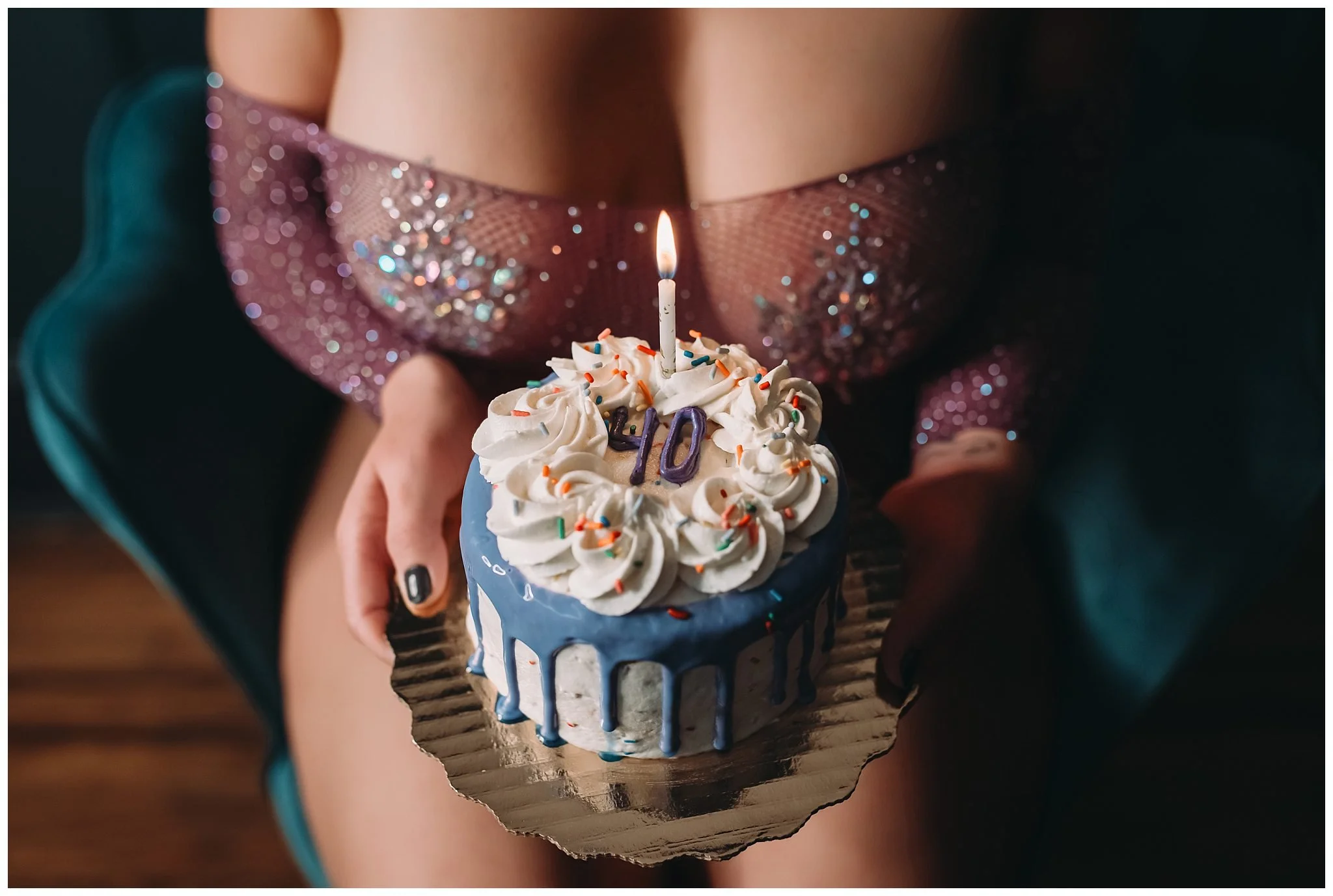 Client holds 40th birthday cake that has lit candle for boudoir photos