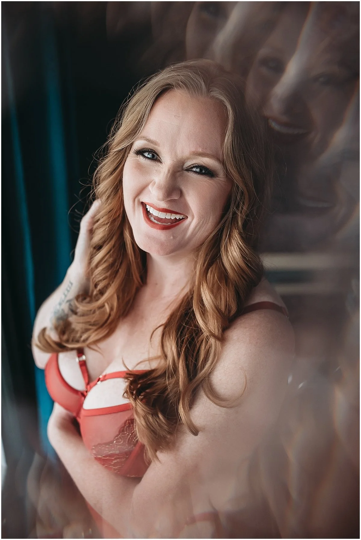 Empowering boudoir photography of a redheaded woman standing in red lingerie, embracing confidence and femininity