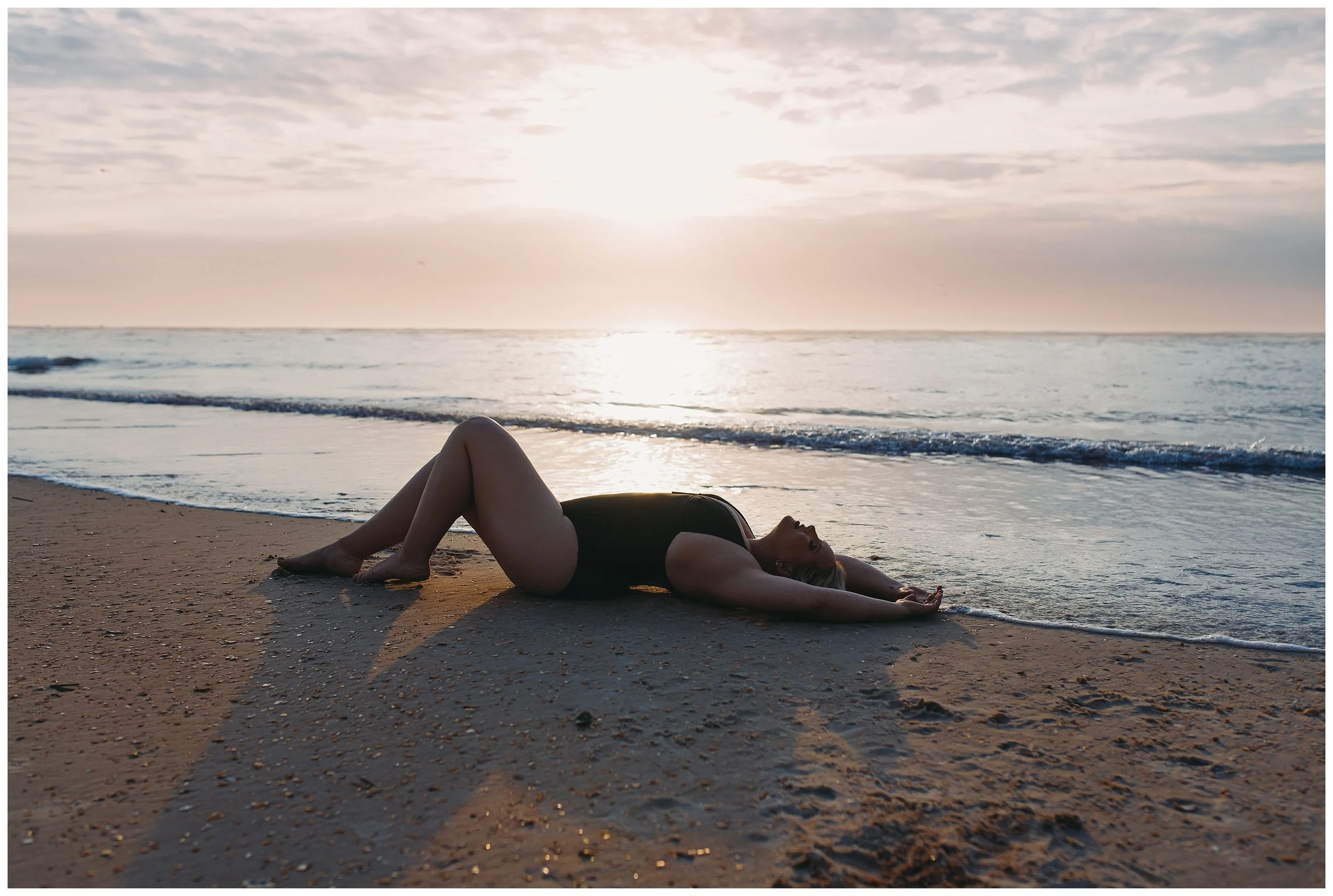Relaxed beach boudoir pose on sand during sunrise in St. Augustine, Florida