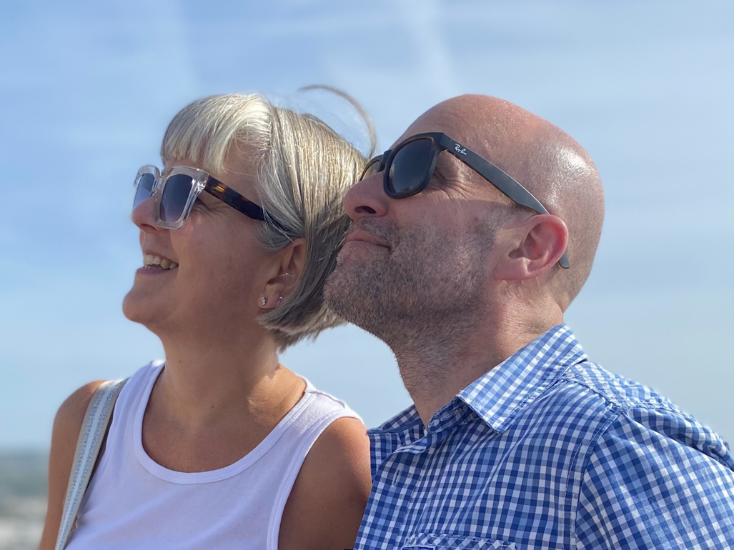 Gavin and Pip Ashton Couple Looking at the shy in sunglasses smiling