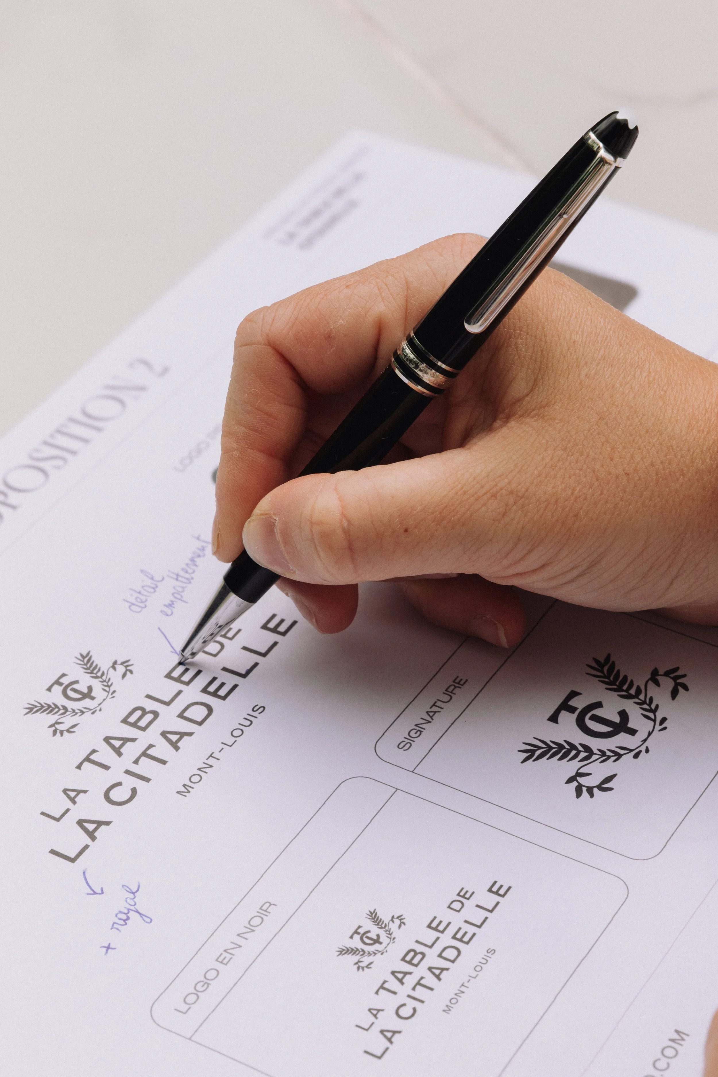 Main écrivant sur une feuille présentant une identité visuelle pour un restaurant gastronomique
