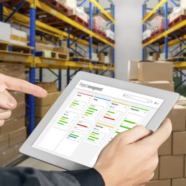Responsable utilisant un logiciel de gestion des stocks sur tablette pour optimiser l’inventaire en entrepôt.