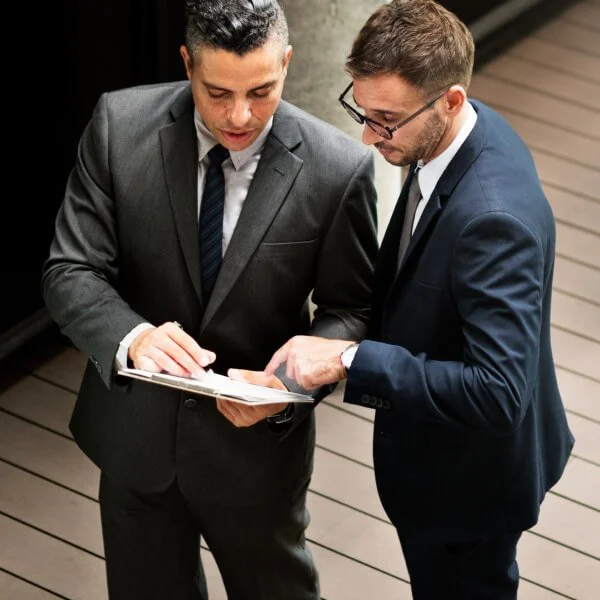 Deux hommes en costume examinant un document, discutant de financement et de valorisation dans un contexte juridique.