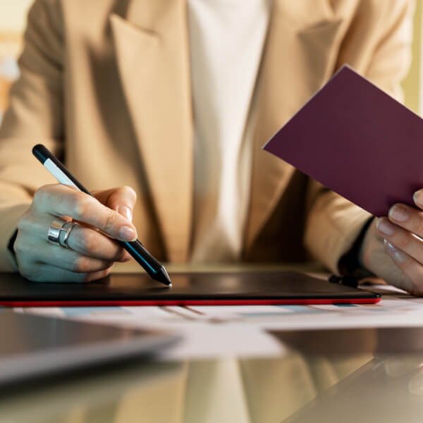 Une femme écrit sur un ordinateur portable avec un passeport, évoquant des considérations transfrontalières canadiennes.