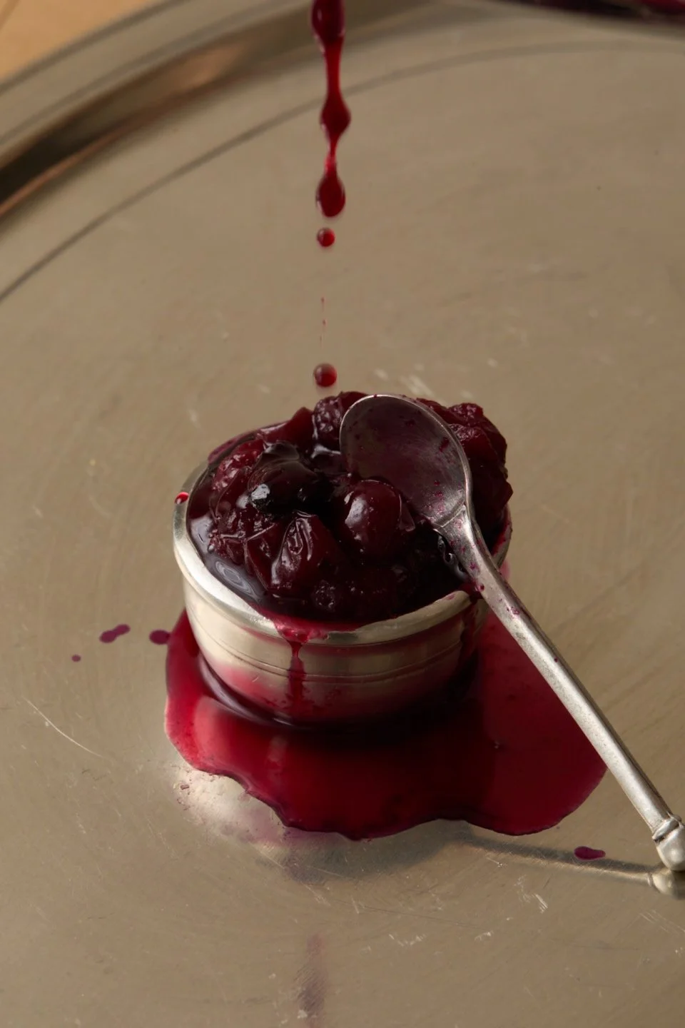 compote dripping into a silver cup of dark berries.