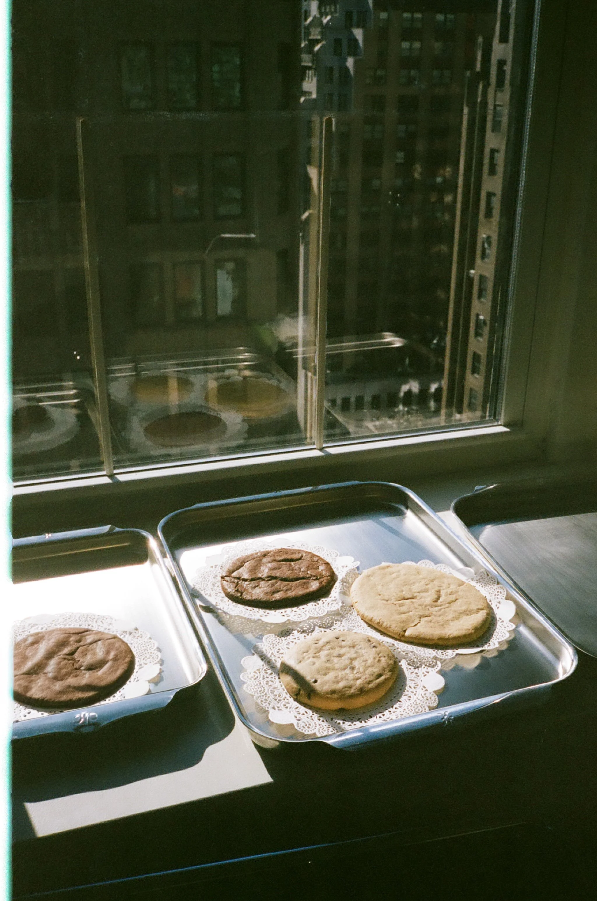 galettes on silver trays by a window, in green light.
