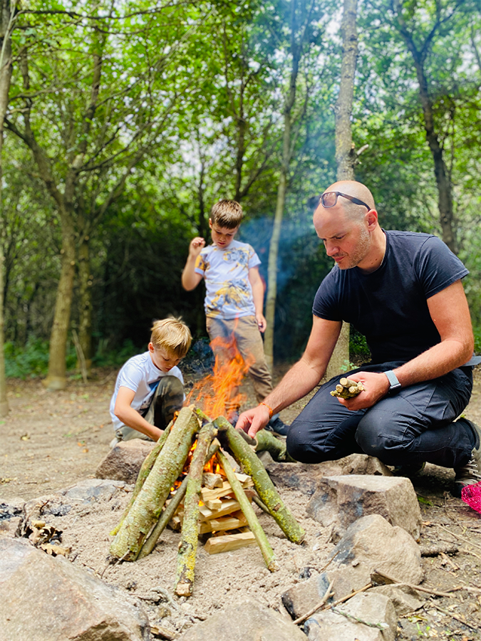 A family building a campfire in the Fire and Stars woodland