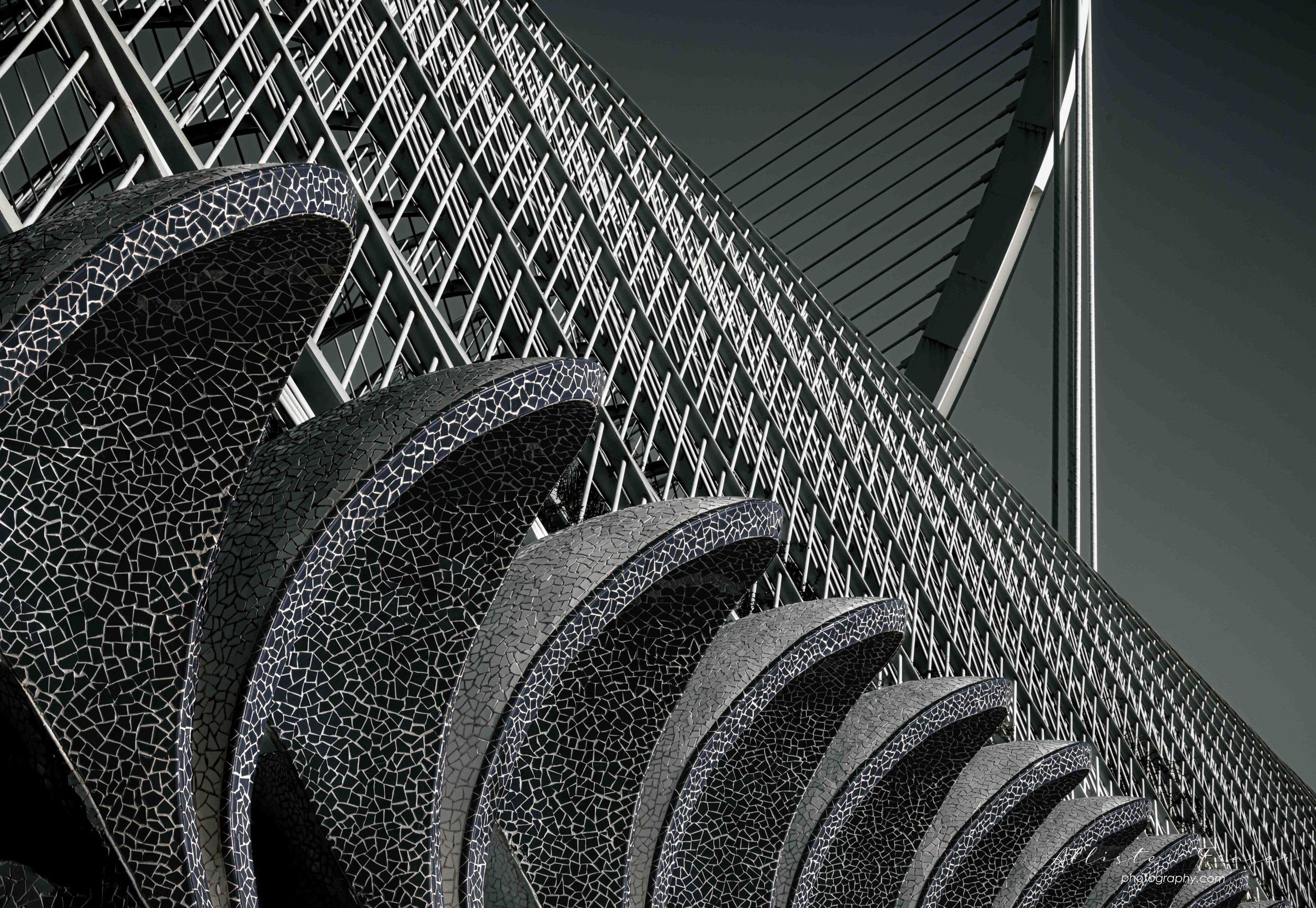l'umbracle roof structure partially hidden by the mosaic shapes on the perimeter with the main support for the l'asset d'or bridge in the background