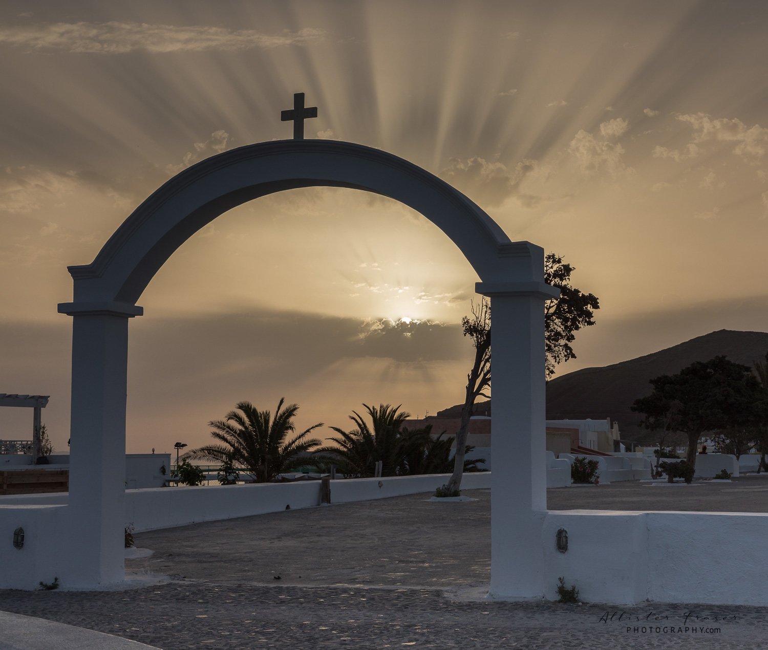 morning sun rays highlighting the "cross on the arch" in oia, santorini