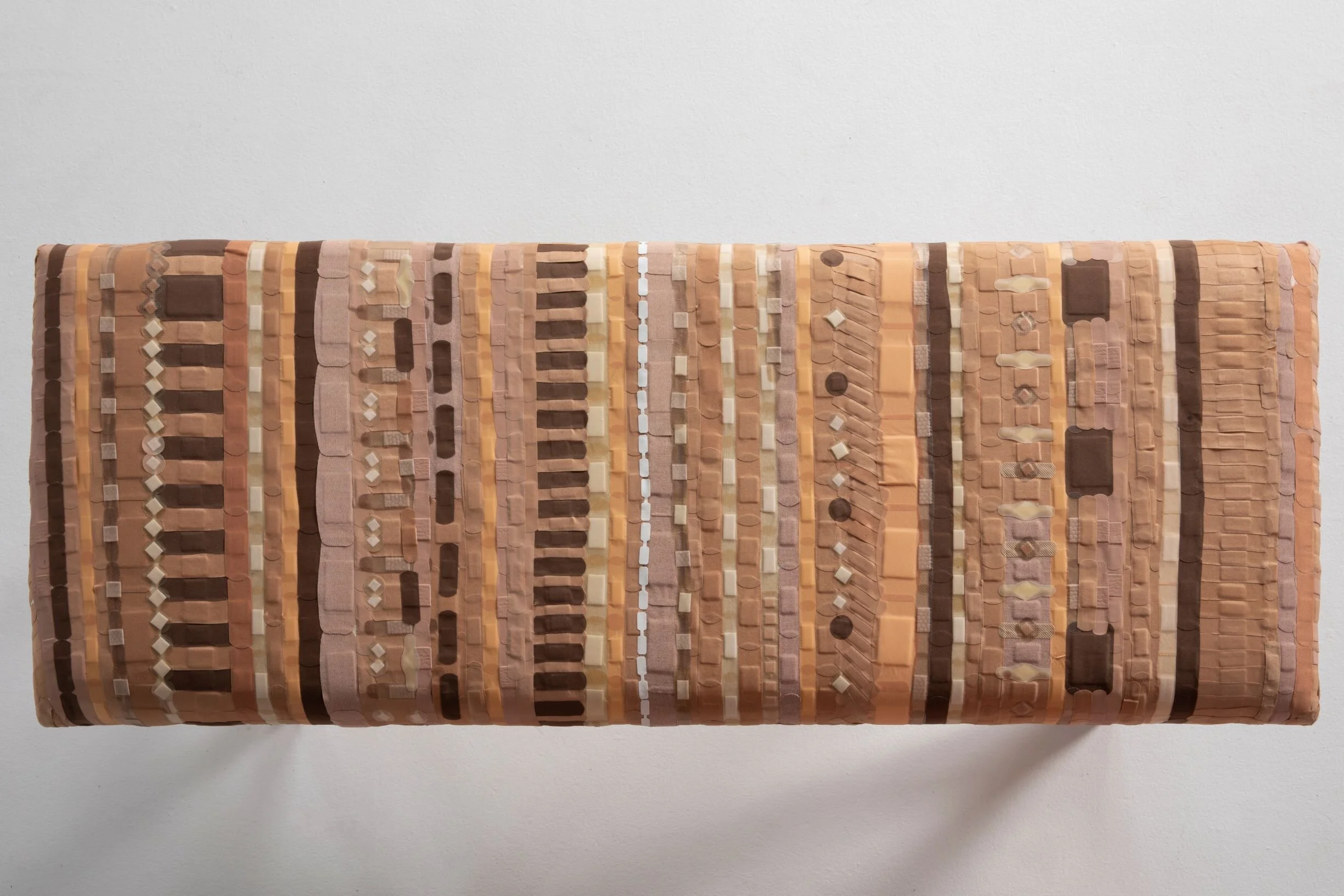 A colorful woven textile with vertical stripes in various shades of brown, beige, pink, and orange, displayed against a plain white background.