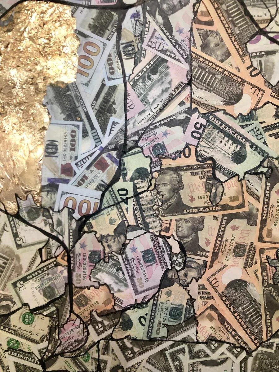 A collage of various U.S. paper currency notes inside a cracked glass frame.