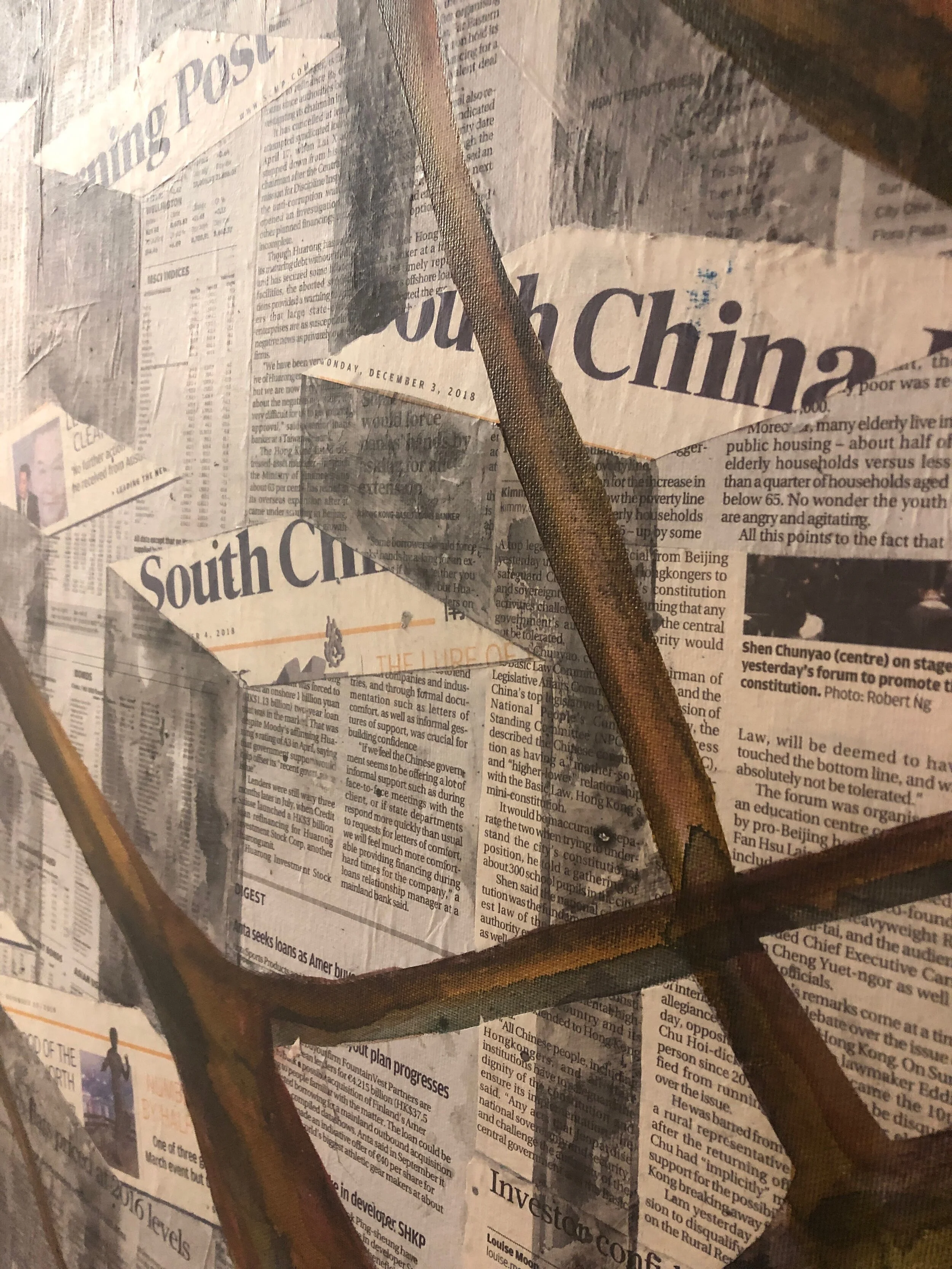 Newspaper articles and headlines on a wall with a large, rusty metal frame in front.