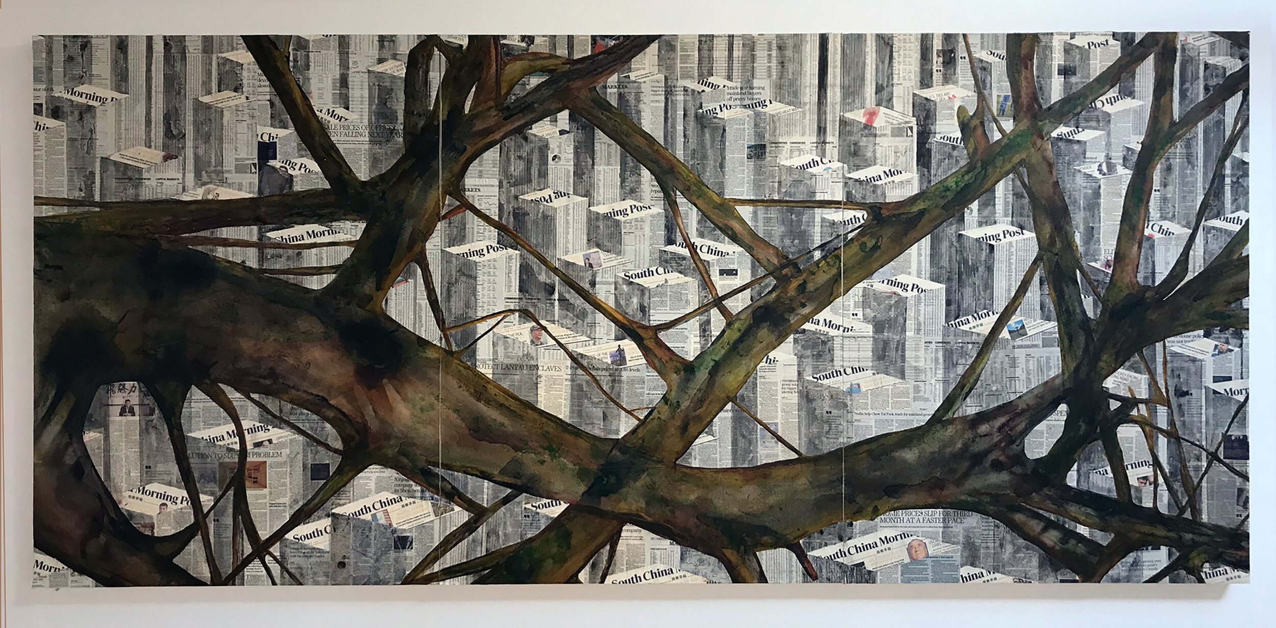 A large painting of tree branches painted over a background made of layered newspaper pages.