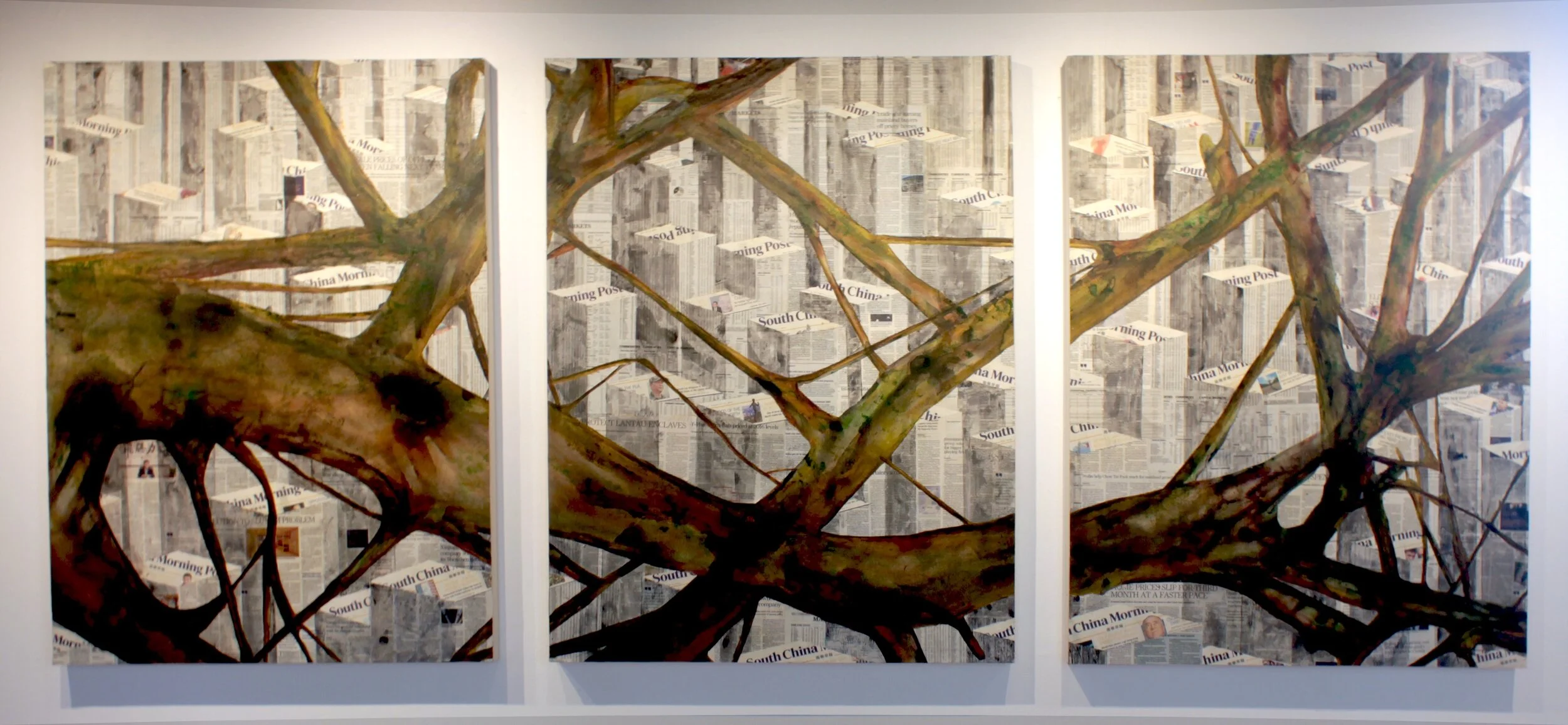 A triptych art piece depicting a tree with sprawling branches painted over a background made of overlapping newspaper pages, displayed on a white wall.