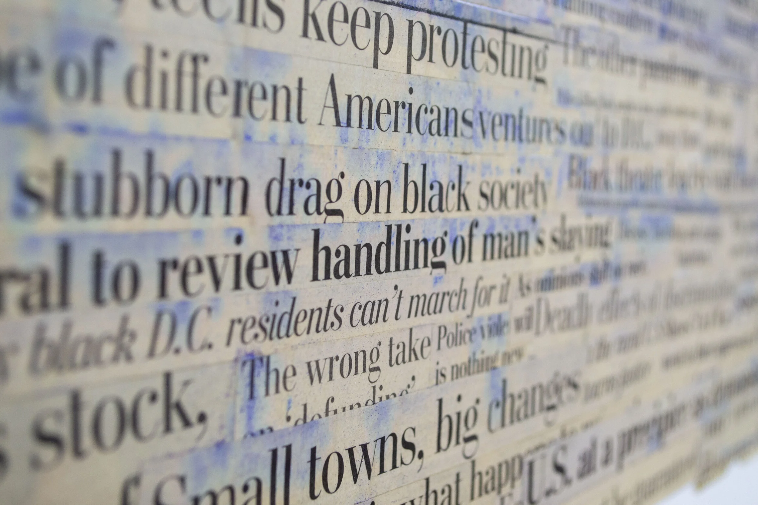 Close-up of a newspaper with black text and blue ink smudges on the paper.