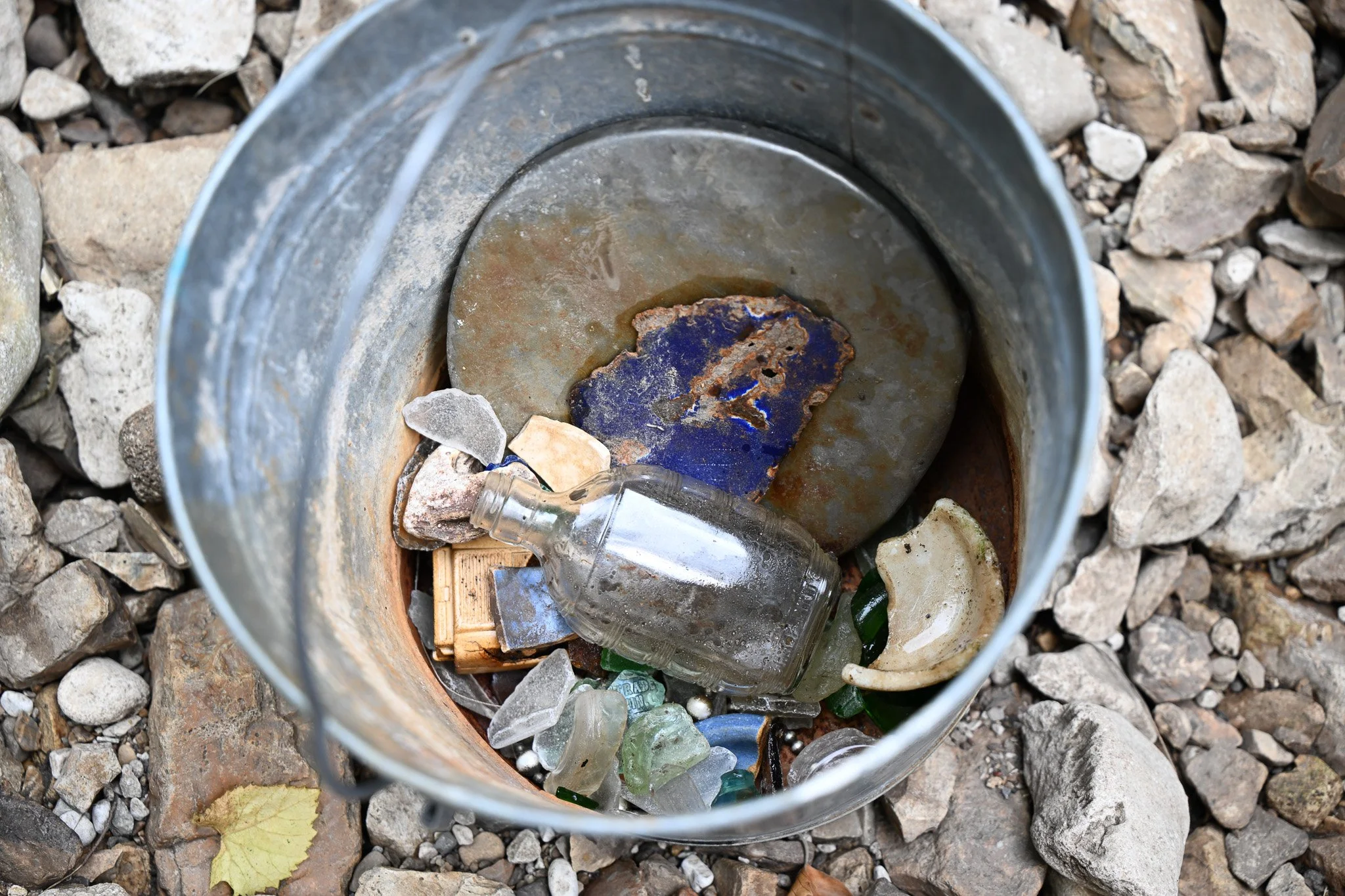 Various pieces of colored glass and broken pottery pieces sit in the bucket Ali Freeman uses to collect her items on Wednesday, June 24, 2026, at Flat Branch Creek in Columbia. She takes the collected items and uses them for art pieces she puts toget