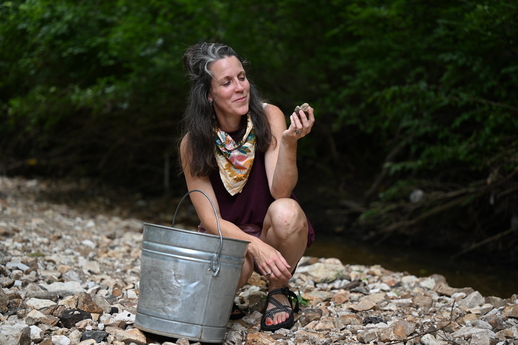 Local artist Ali Freeman smiles as she finds a piece of pottery  on Wednesday, June 24, 2026, at Flat Branch Creek in Columbia. “Coming out and looking for stuff makes me feel like a kid again,” Freeman said.