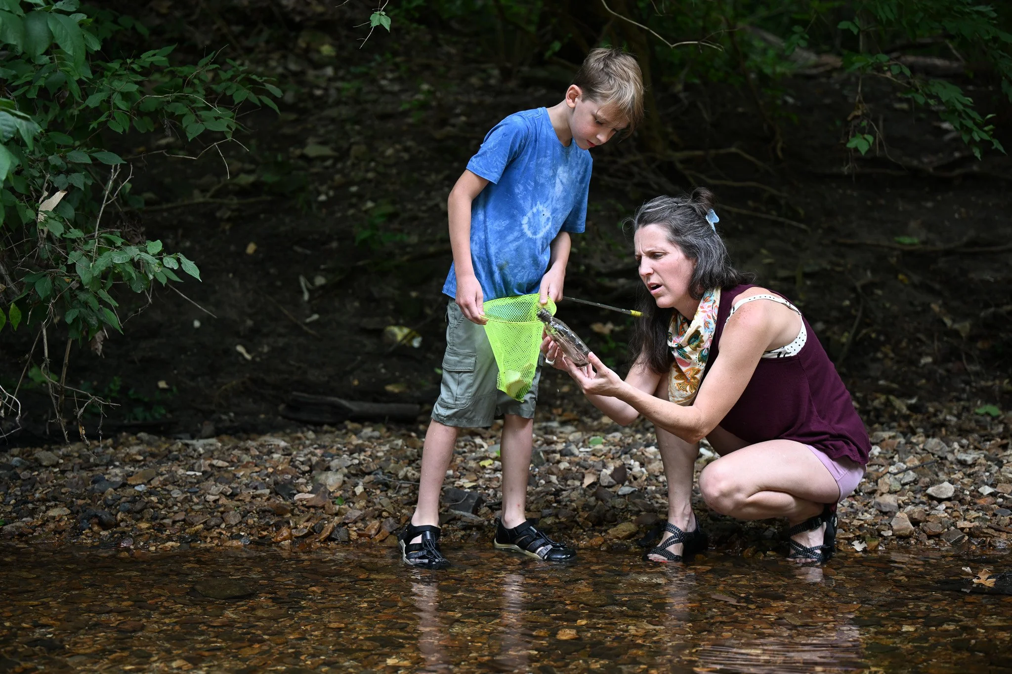 Ali Freeman reads the inscription of a glass bottle to her son Lochlan, 8, on Wednesday, June 24, 2026, at Flat Branch Creek in Columbia. Freeman is also a second grade teacher for the City Garden School in Columbia. 