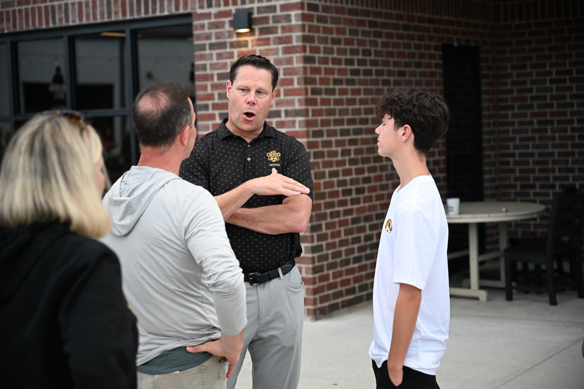 From left Doug Quinn, Mizzou Athletic Director Laird Veetch and Alex Quinn, 14, talk after the team and coaches introductions at the Zou to You event on Wednesday, June 24, 2026, at the Kitchen Bar and Grill in Columbia. The Zou to You tour hit 9 dif
