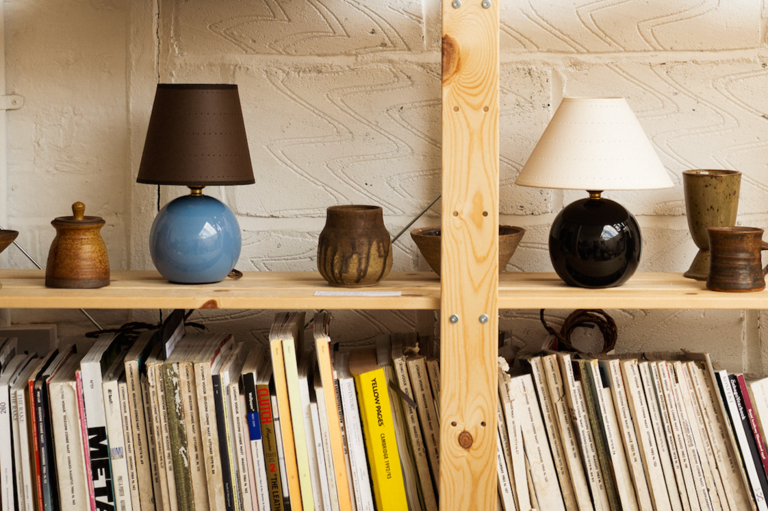A bookcase wtih magazine and two round lamps by Hum London, one in black and the other blue