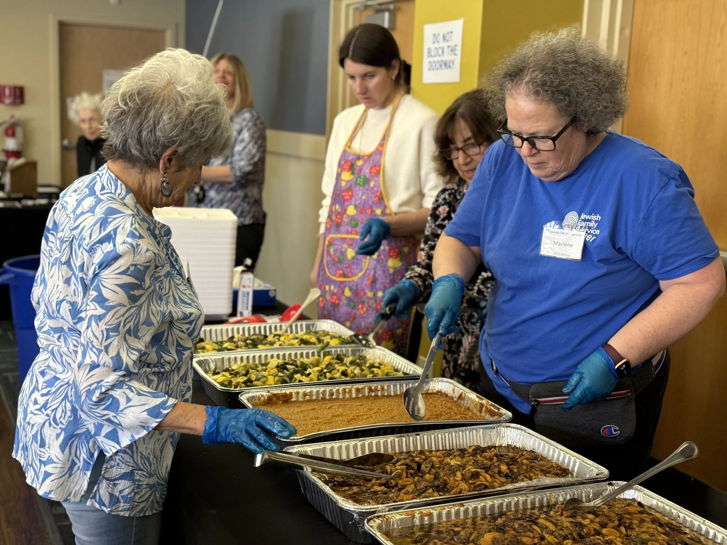 People serving food from a buffet table.