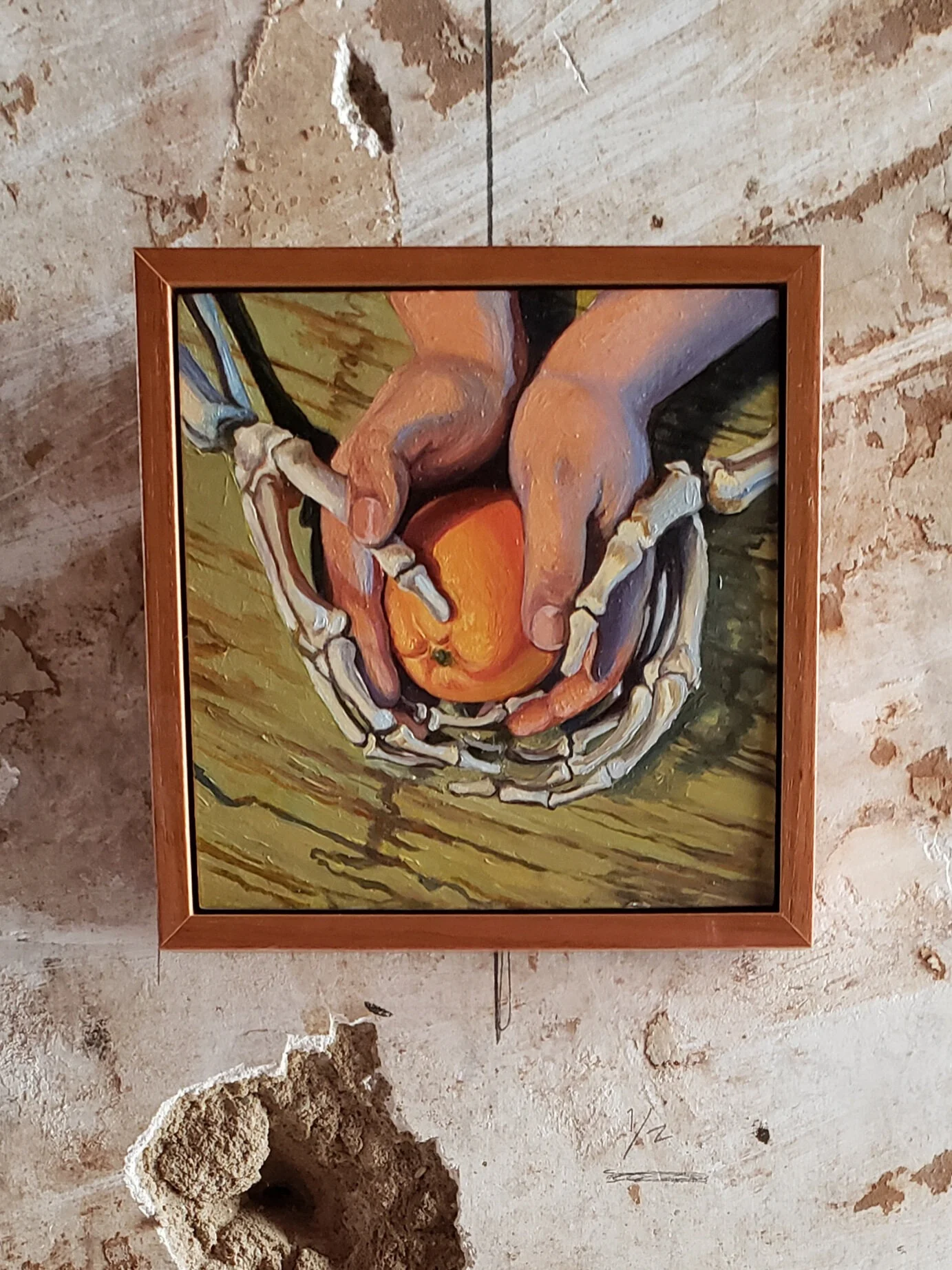 Painting of hands with skeletal bones holding an orange on a wooden surface.