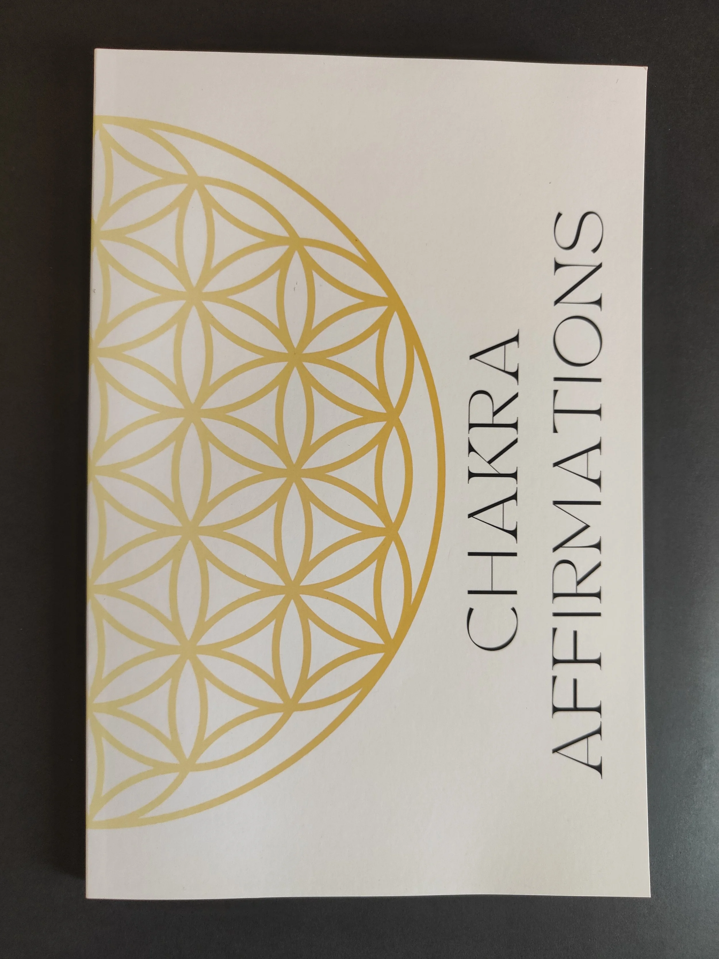 A white box with gold geometric circular pattern and black text reading 'Chakra Affirmations'.