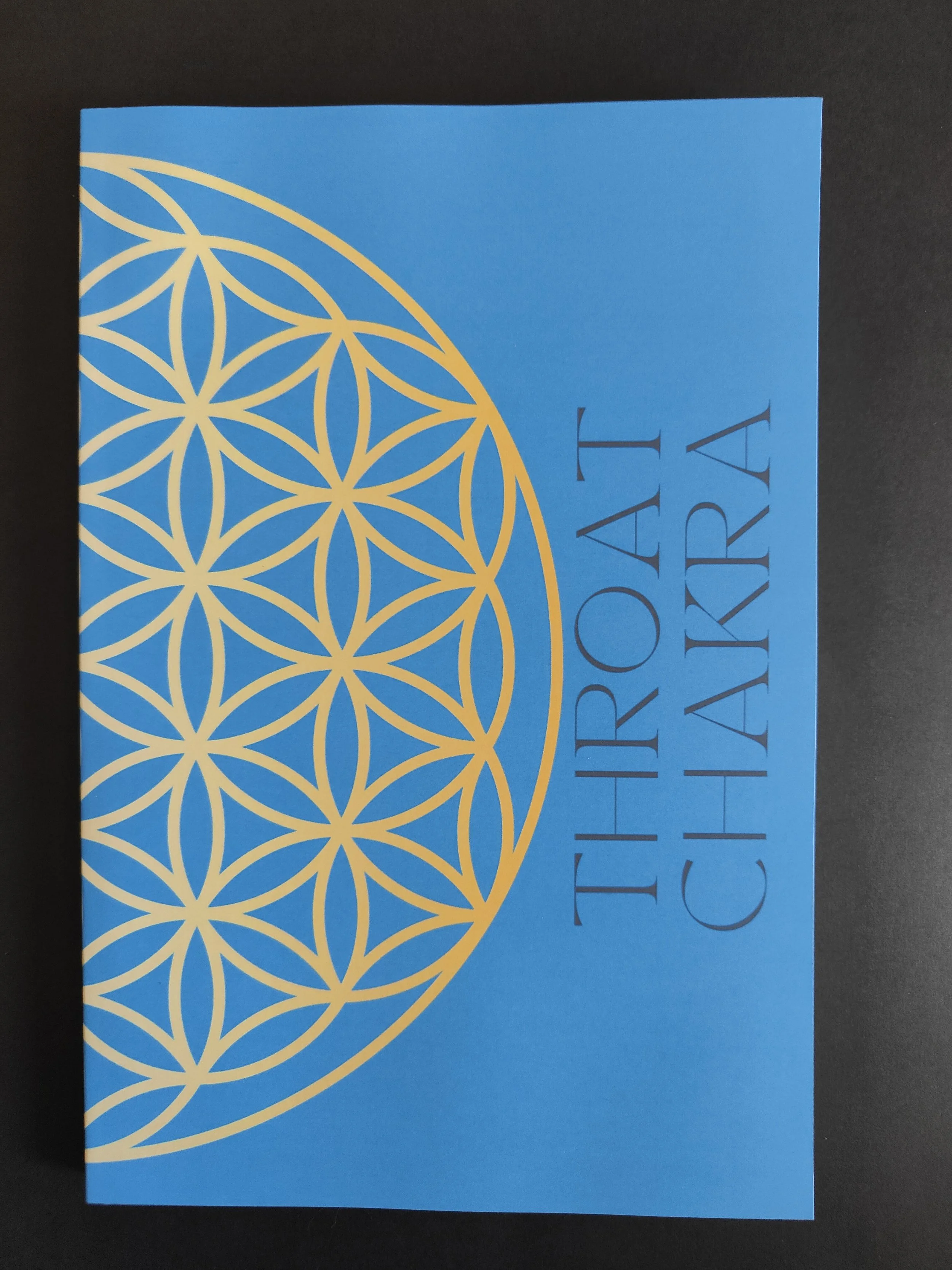 Front cover of a turquoise card with a gold geometric flower of life pattern and the words "TRİO PATI ÇİHARİ" in dark blue uppercase letters.