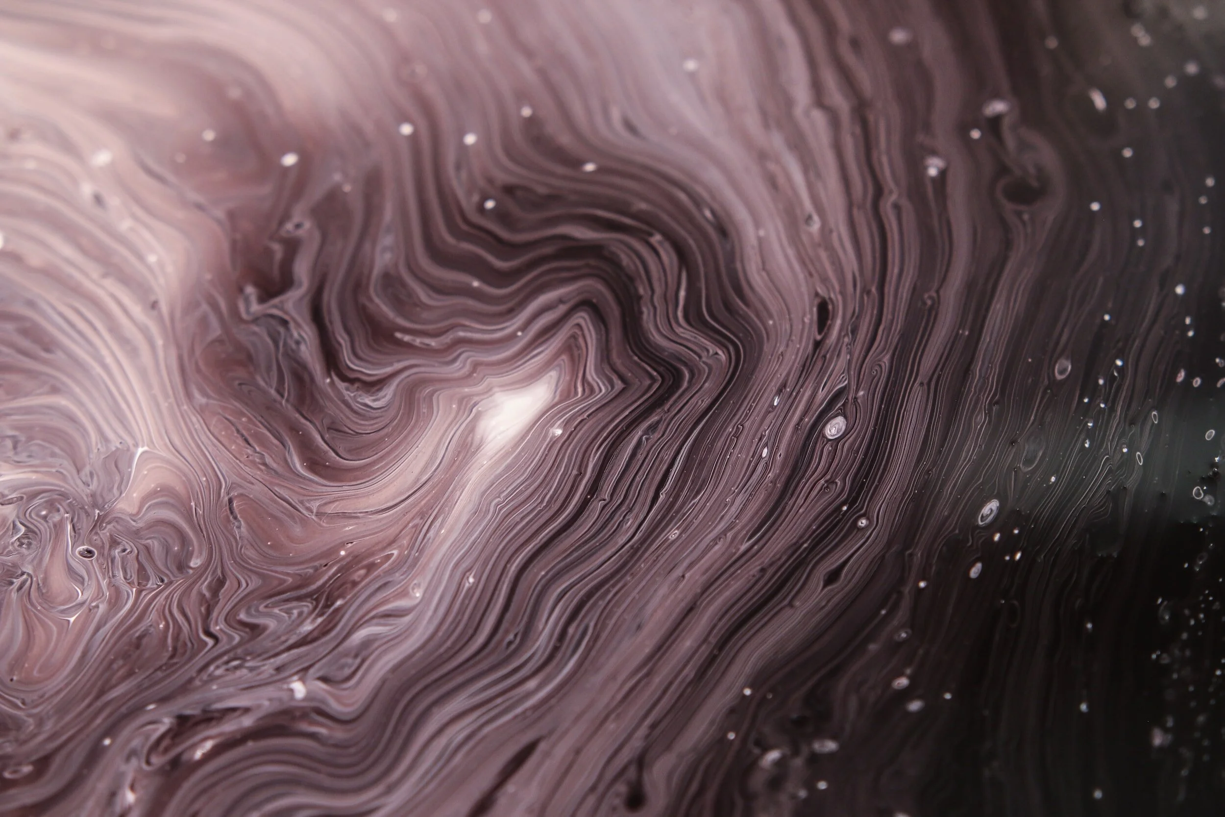 Close-up view of swirling pink, black, and white marbled pattern with small air bubbles.