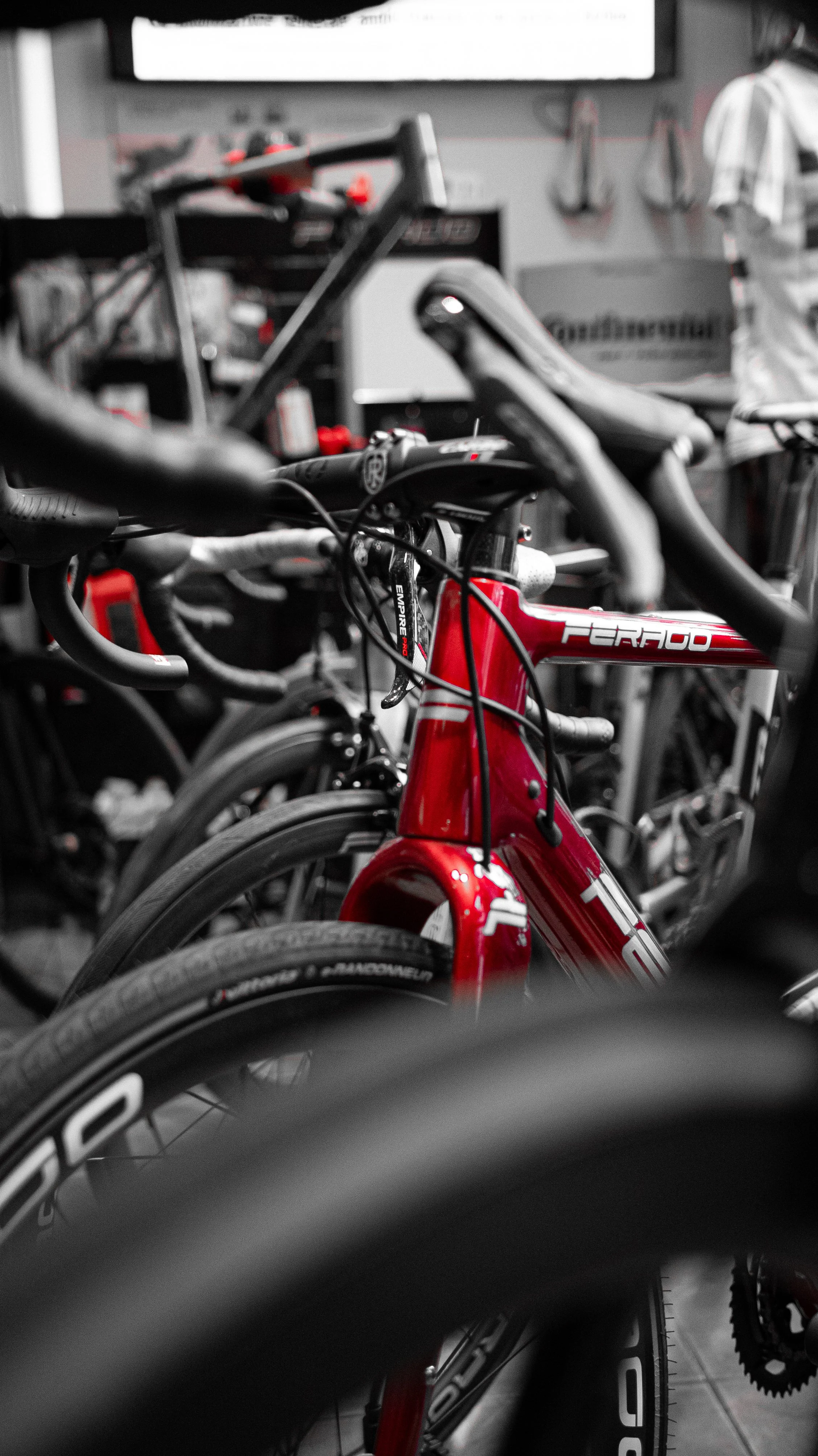 Una bici da corsa rossa nel museo o negozio di biciclette, con altre biciclette e attrezzi sullo sfondo.