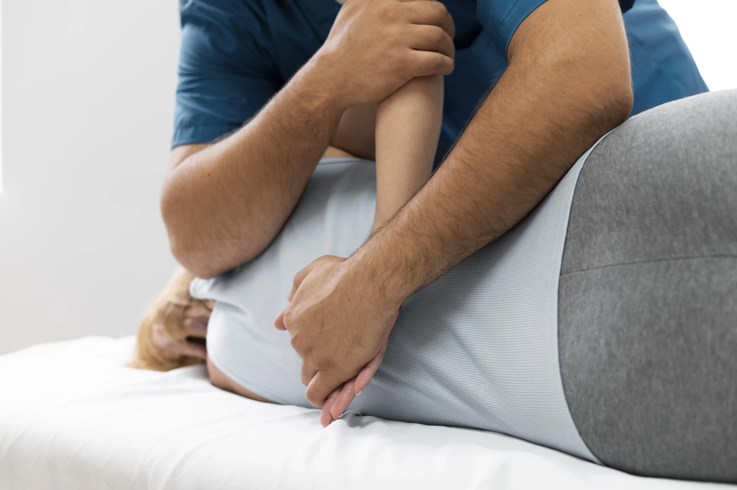 A man providing first aid to a woman lying on a bed, performing rescue breaths by blowing into her mouth.