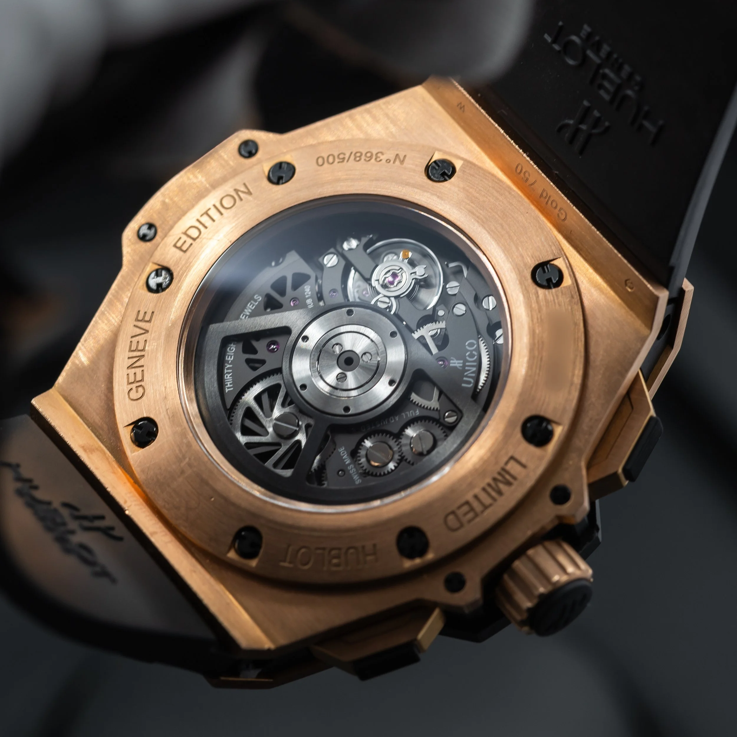 Close-up of a luxury watch with a black strap and a rose gold case, showcasing its skeletonized dial with visible gears and mechanical movement.
