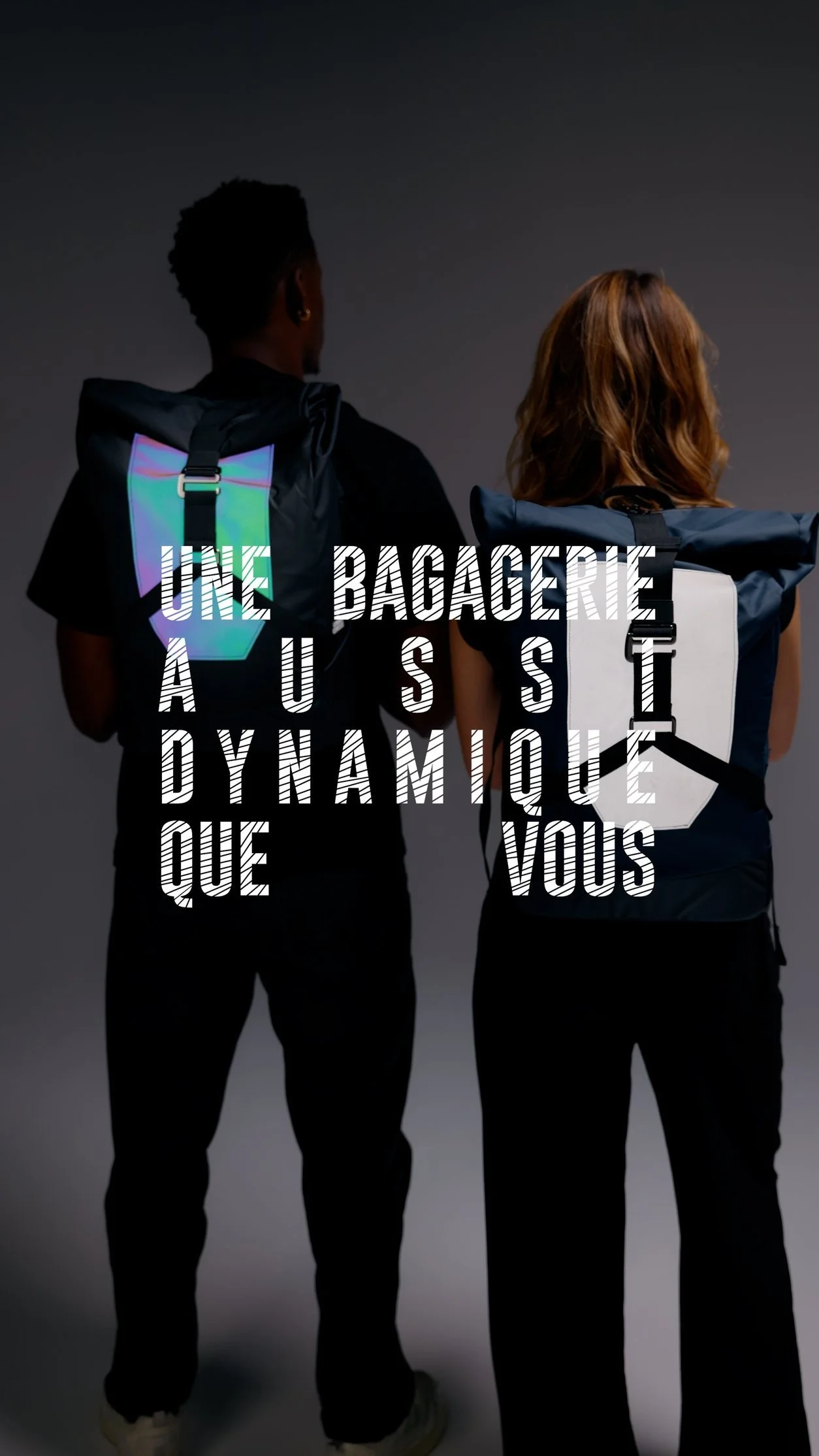Deux personnes avec des sacs à dos regardant vers l'arrière, un fond sombre, texte en français superposé : "Une bagagerie AUSSI dynamique que vous".