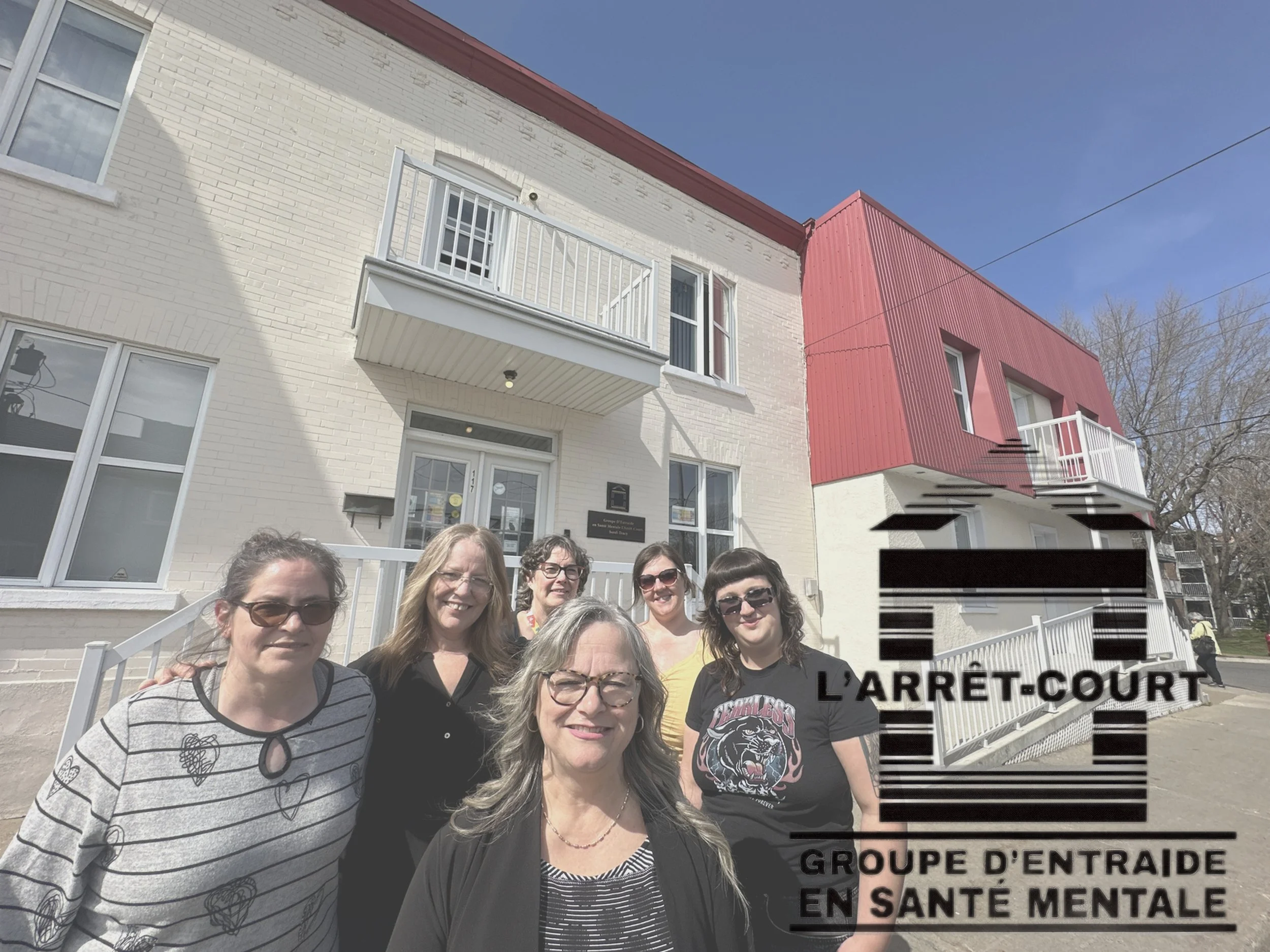 Groupe de cinq femmes devant un bâtiment. Il y a un logo en superposition indiquant 'L'arret-court, groupe d'entraide en santé mentale'.